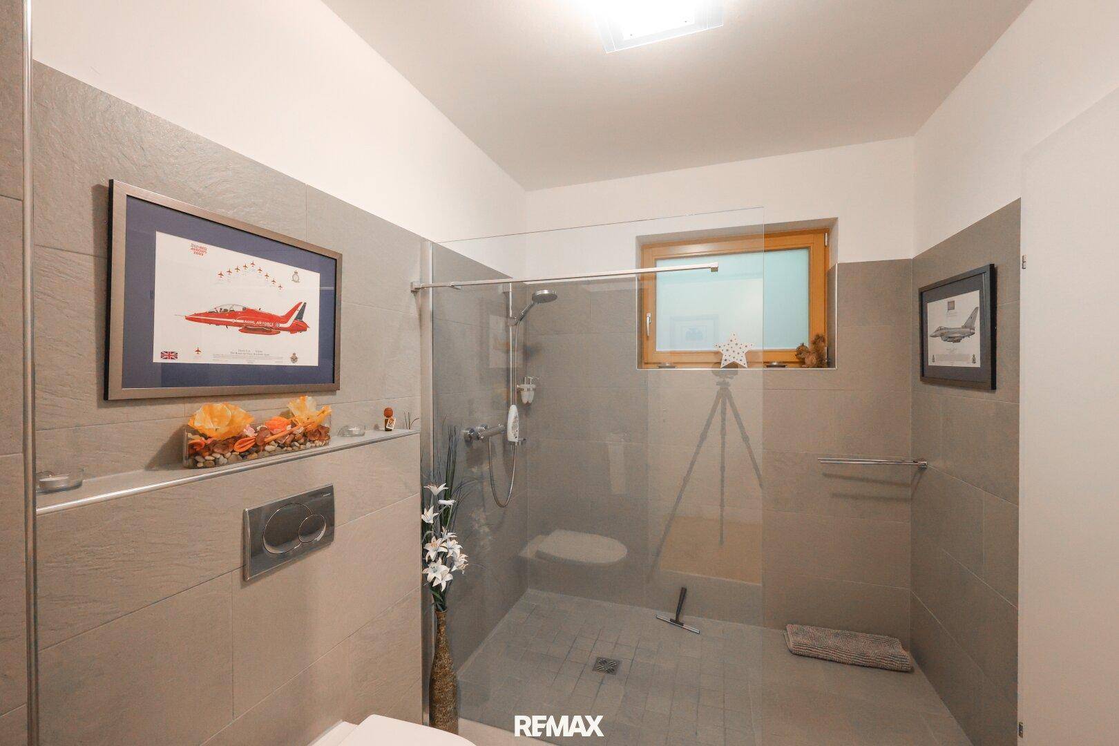 Helles Badezimmer mit Toilette, begehbarer Dusche und einem Fenster für natürliche Belüftung.