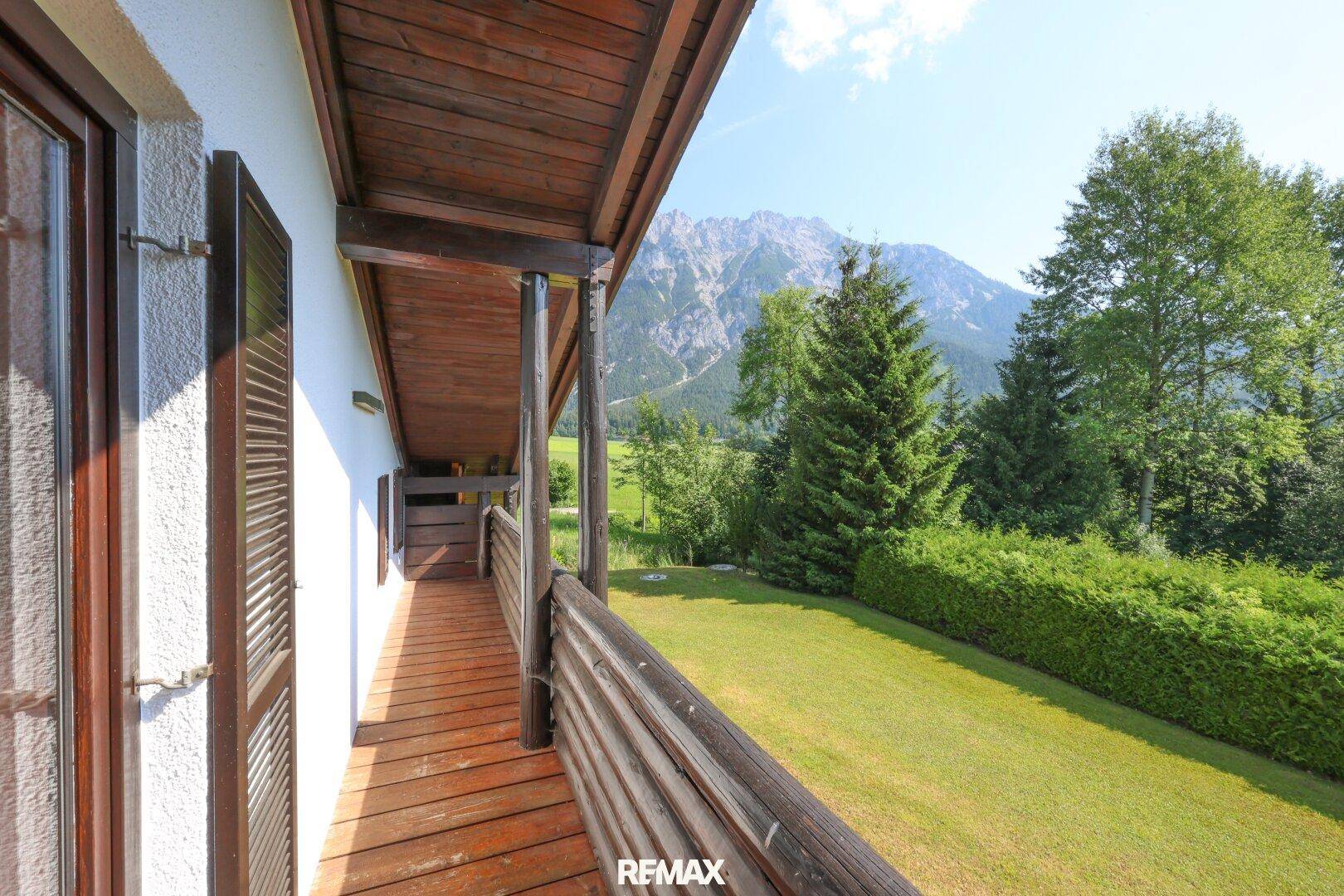 Langer Holzbalkon mit Blick auf die Berge und die grüne Landschaft.