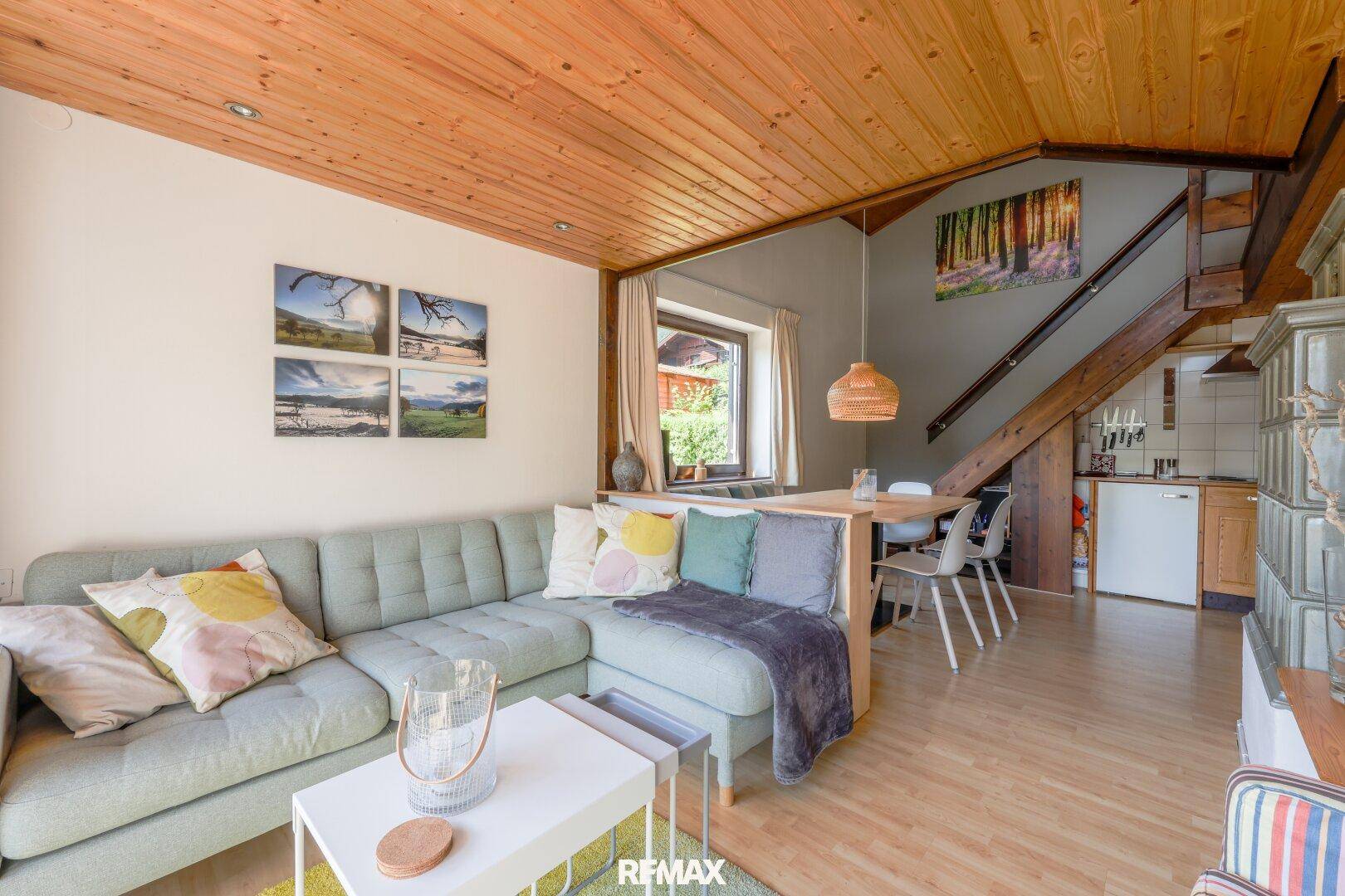 Offener Wohnbereich mit bequemer Couch, Holzbalkendecke und integriertem Essbereich.