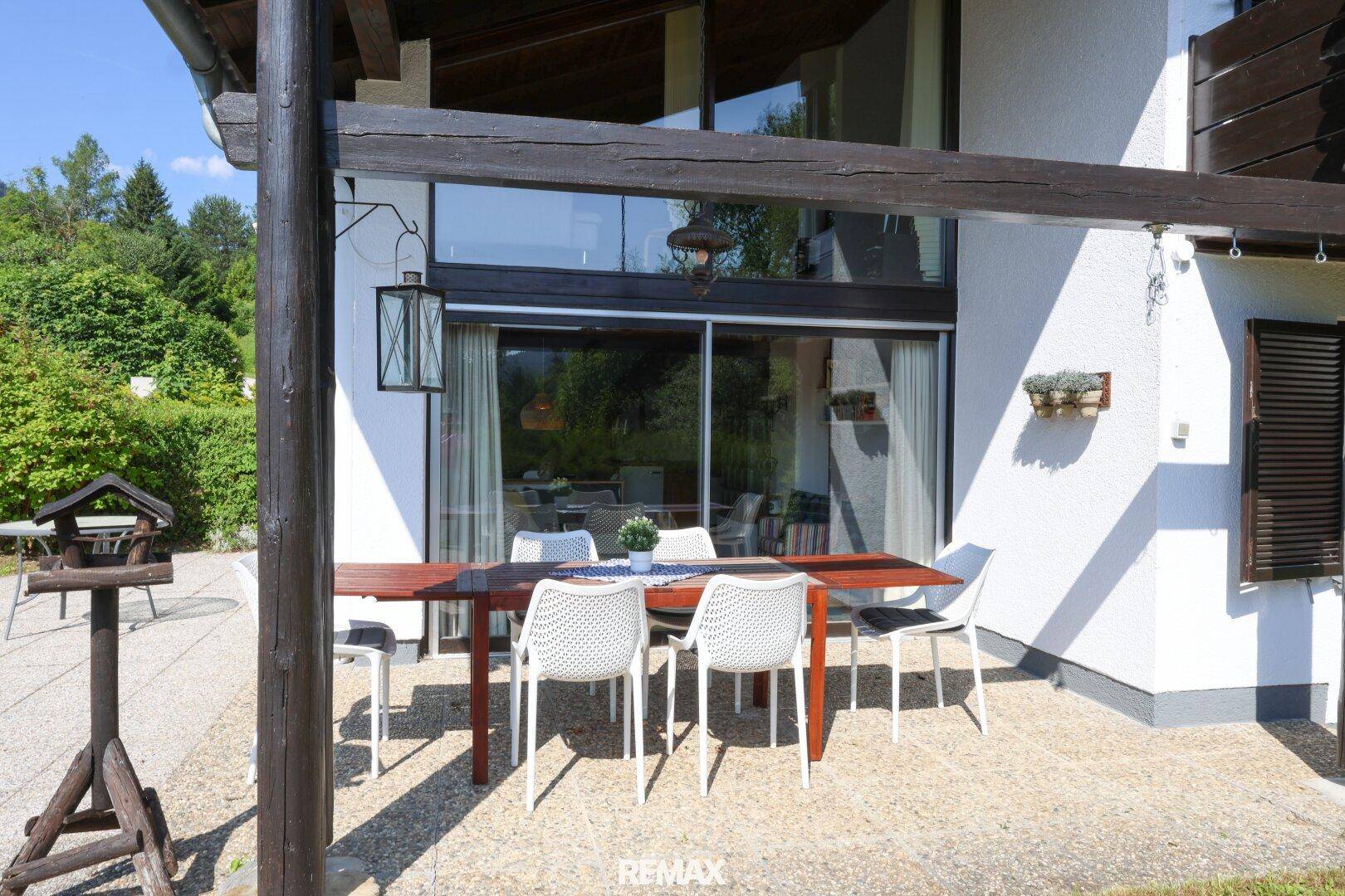 Detailansicht der Terrasse mit Esstisch und Stühlen, umgeben von üppigem Grün.