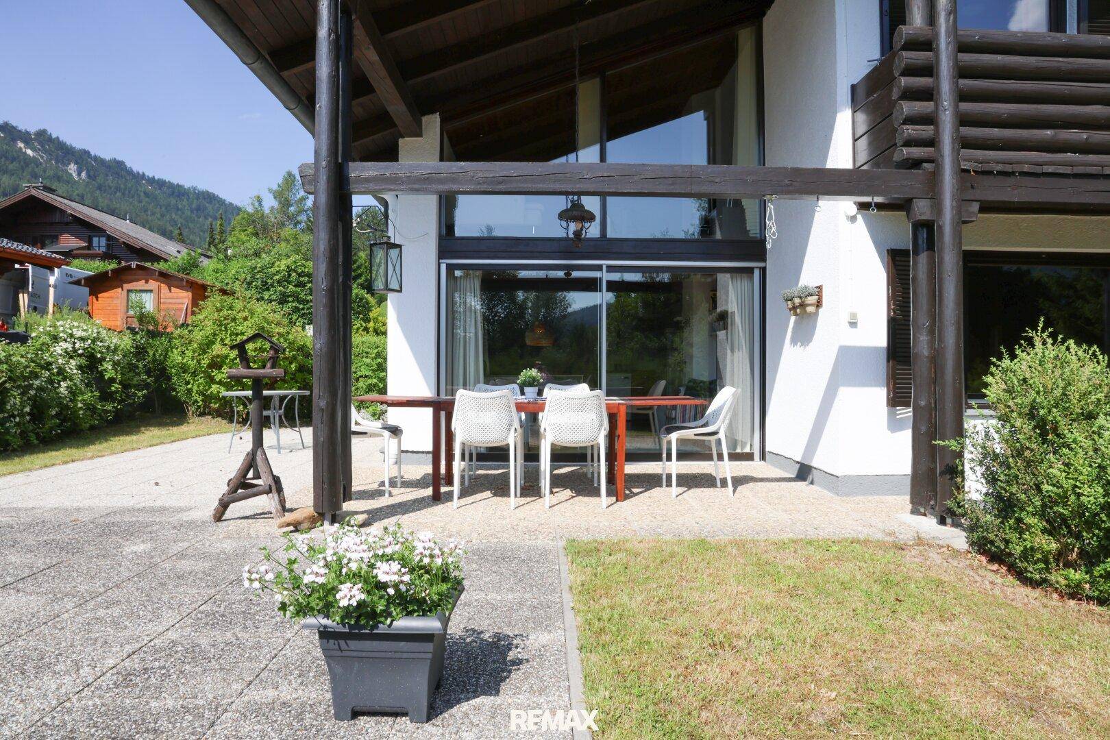Gemütliche Terrasse mit Esstisch und Stühlen vor dem Haus, umgeben von Grün.
