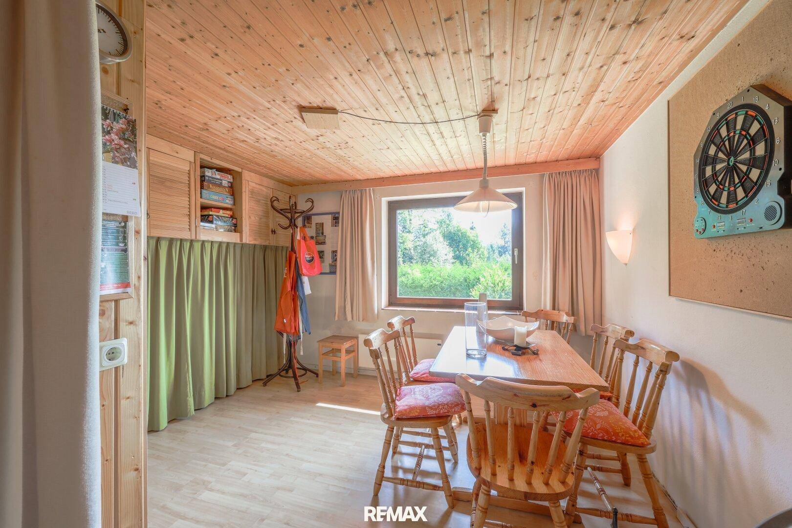 Rustikaler Essbereich mit Holztisch, Stühlen und Holzverkleidung an Decke und Wänden.