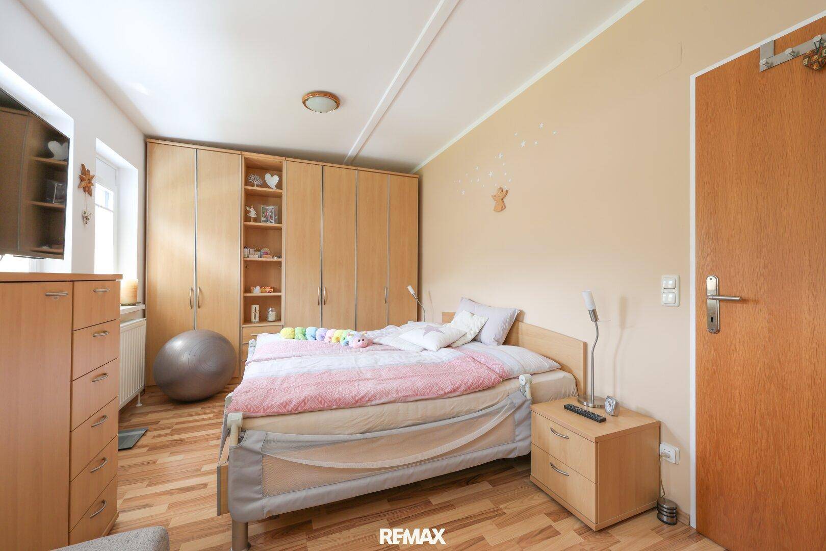 Geräumiges Schlafzimmer mit großem Kleiderschrank, Doppelbett und Laminatboden.