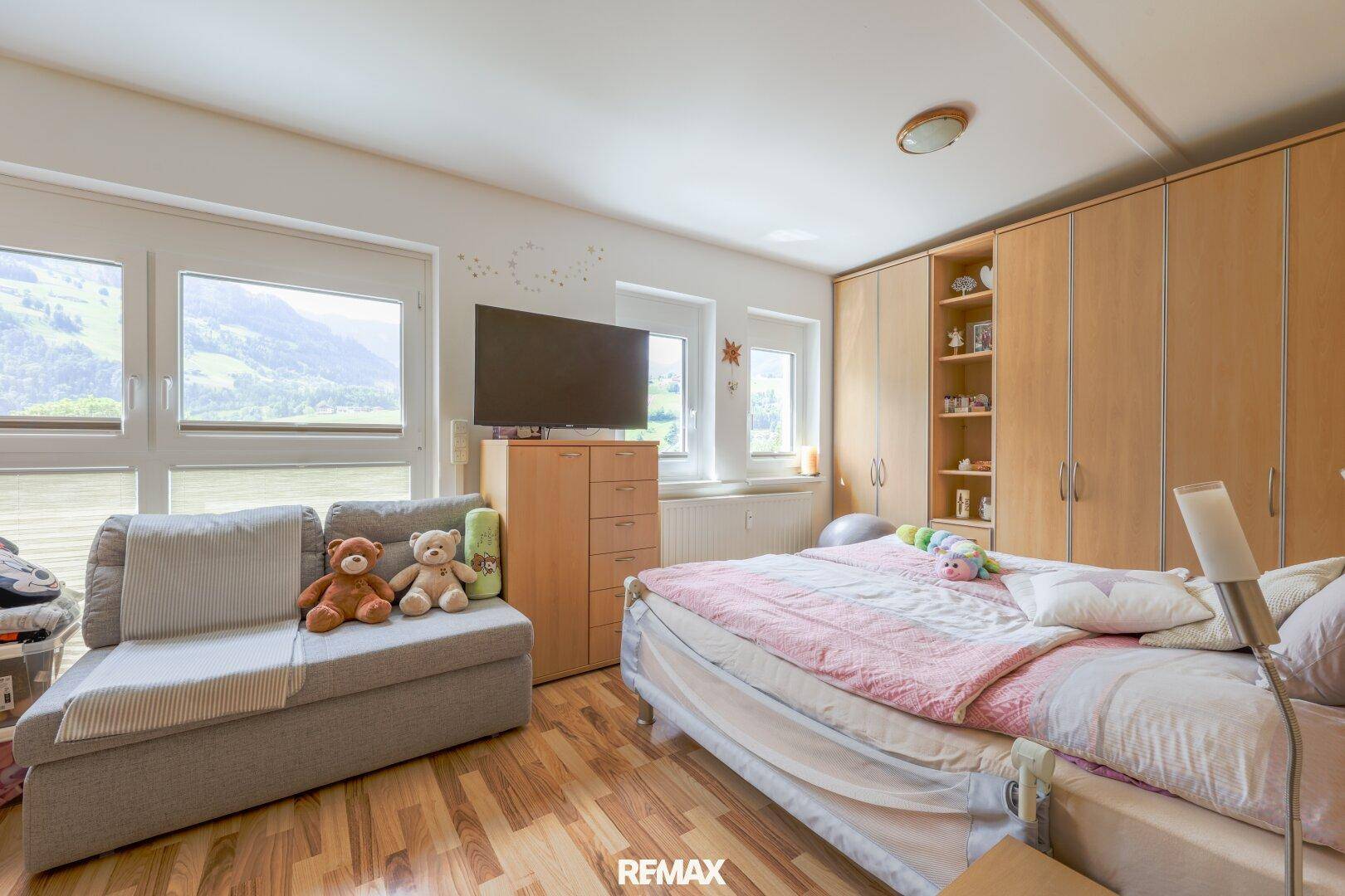 Helles Schlafzimmer mit Bergblick, großem Fenster und integriertem Kleiderschrank.