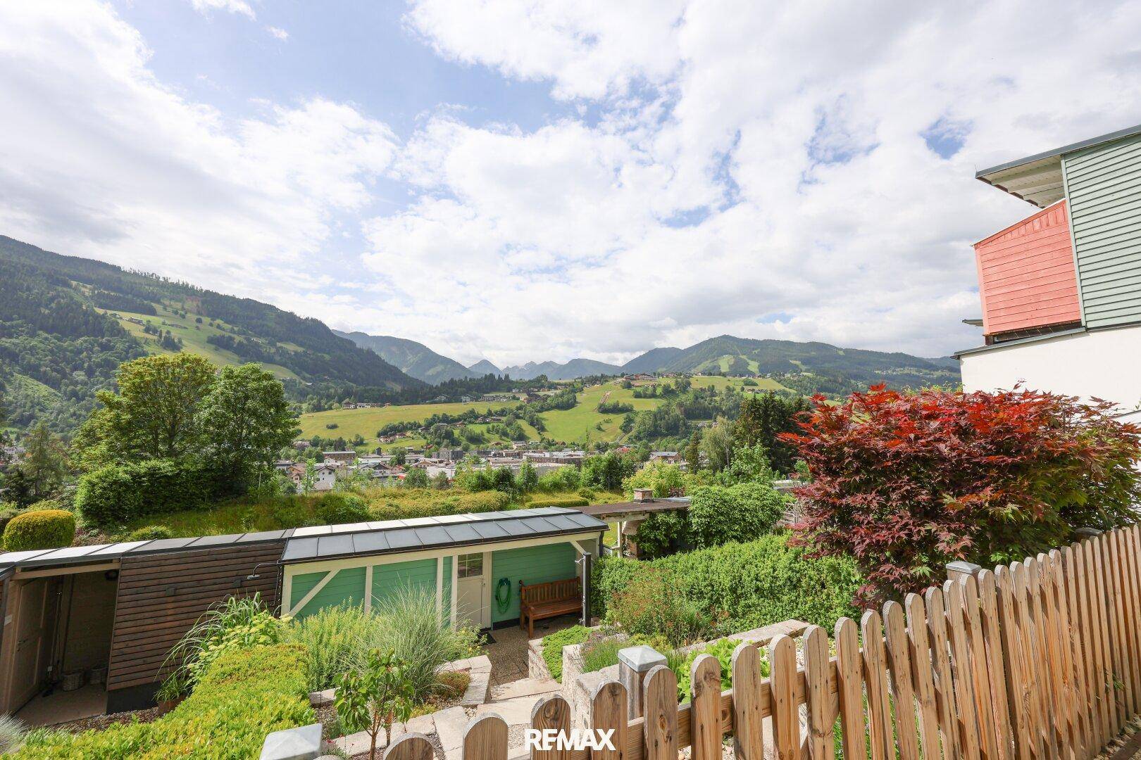 Gartenbereich mit Holzzaun und weitem Blick auf die grüne Berglandschaft.