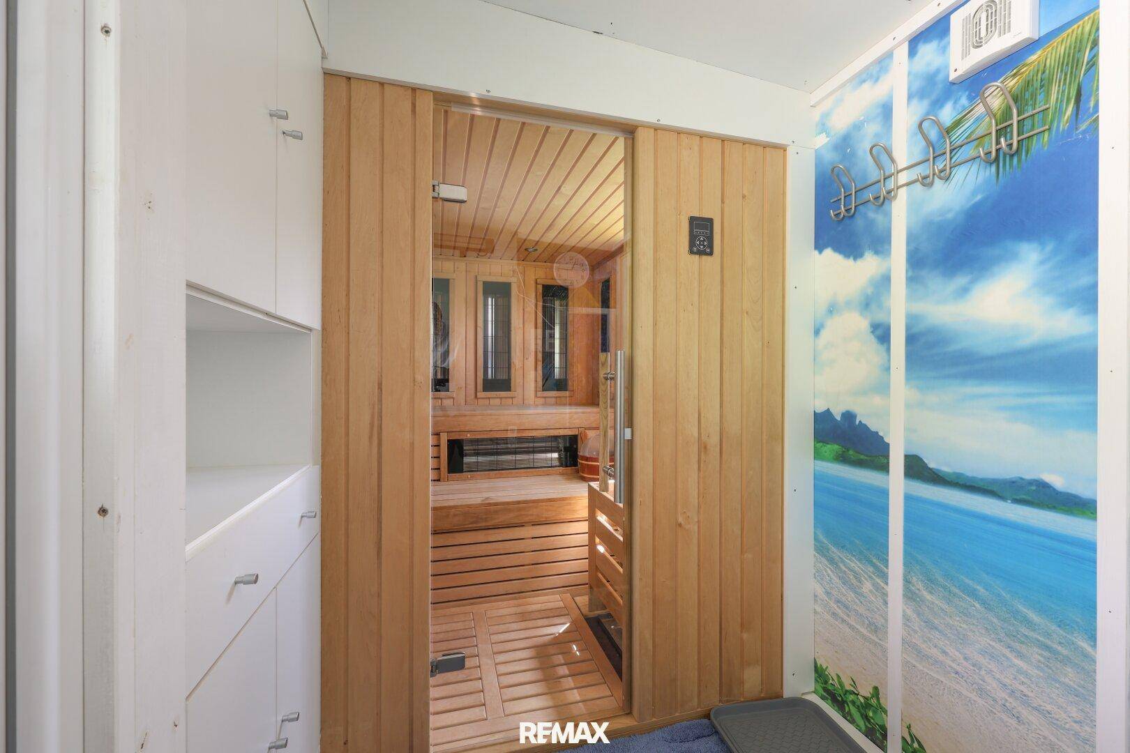 Eingang zu einer privaten Sauna mit Holzwänden und einer Strandtapete im Vorraum.