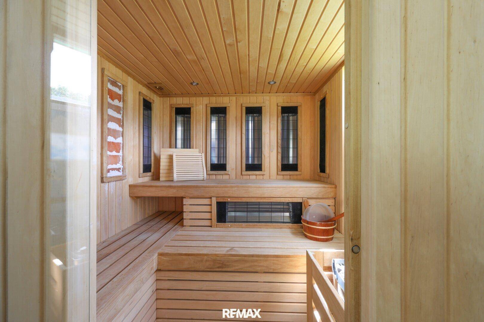 Geräumige Holzsauna mit mehreren Bänken und einem Saunaofen für Entspannung.