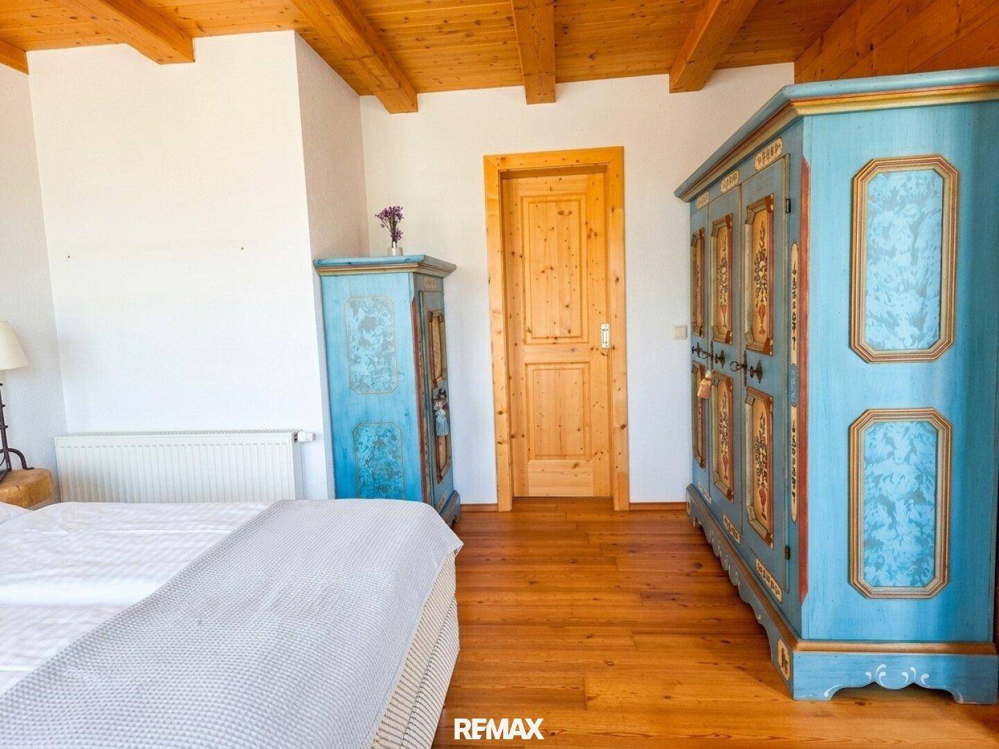 Schlafzimmer mit zwei traditionellen, bemalten Holzschränken und einer Holztür, die den alpinen Stil unterstreichen.