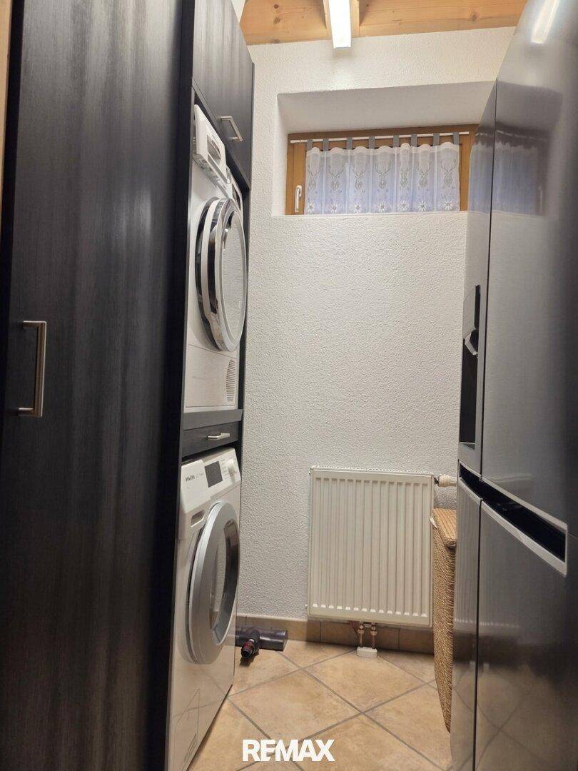 Praktischer Hauswirtschaftsraum mit Waschmaschine, Trockner und Kühlschrank, ideal für den täglichen Bedarf.