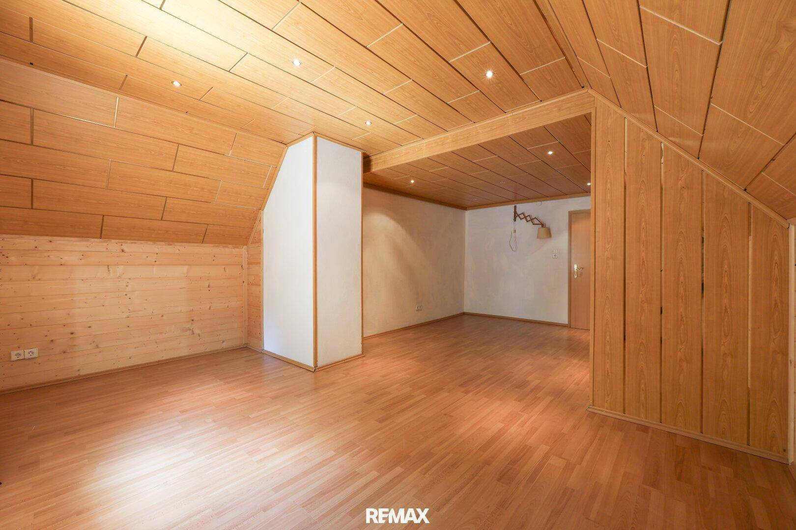 Geräumiger Dachbodenraum mit Holzverkleidung, Laminatboden und Dachschrägen.