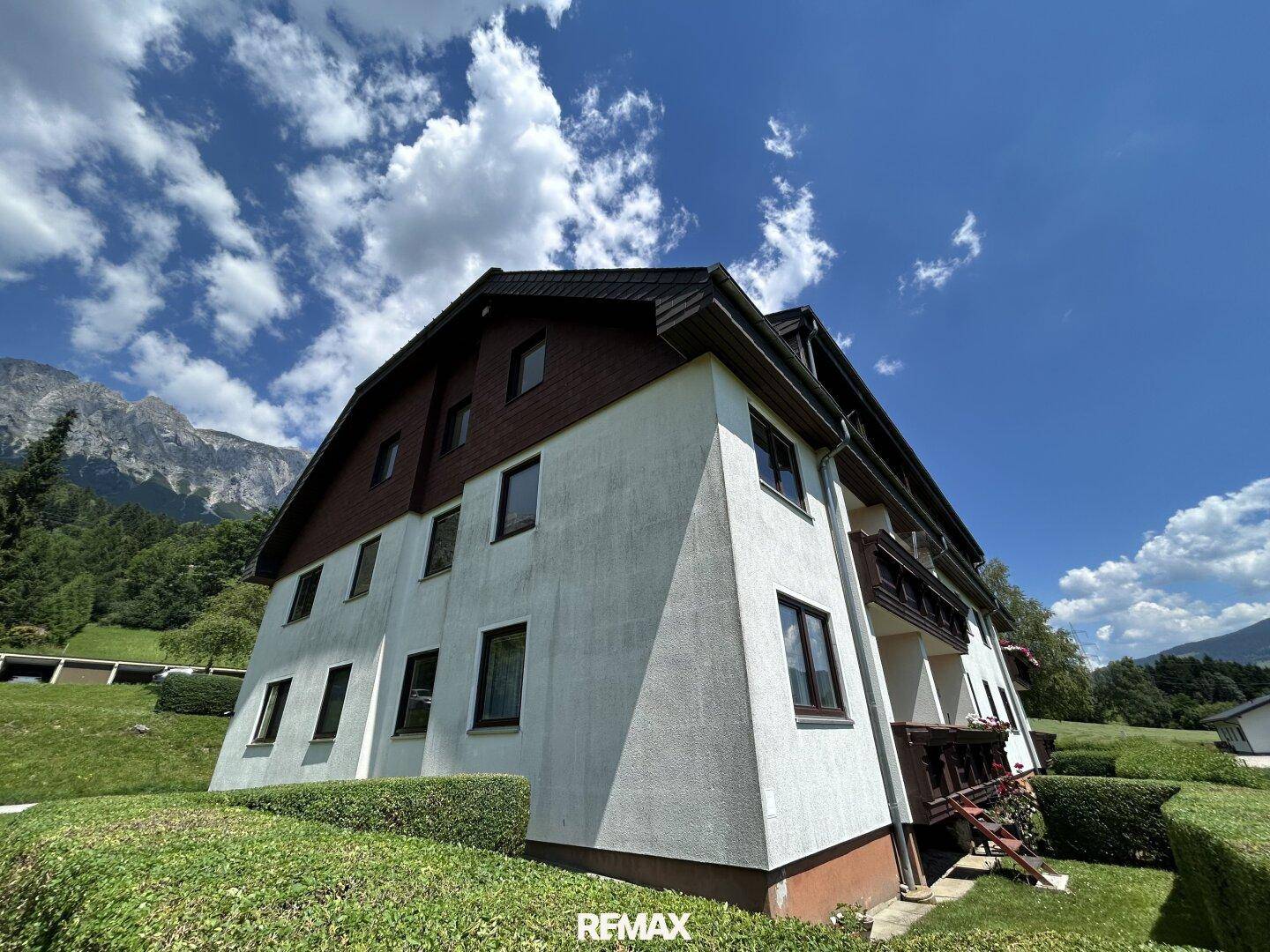 Mehrfamilienhaus mit traditioneller Architektur, Balkonen und Bergblick.
