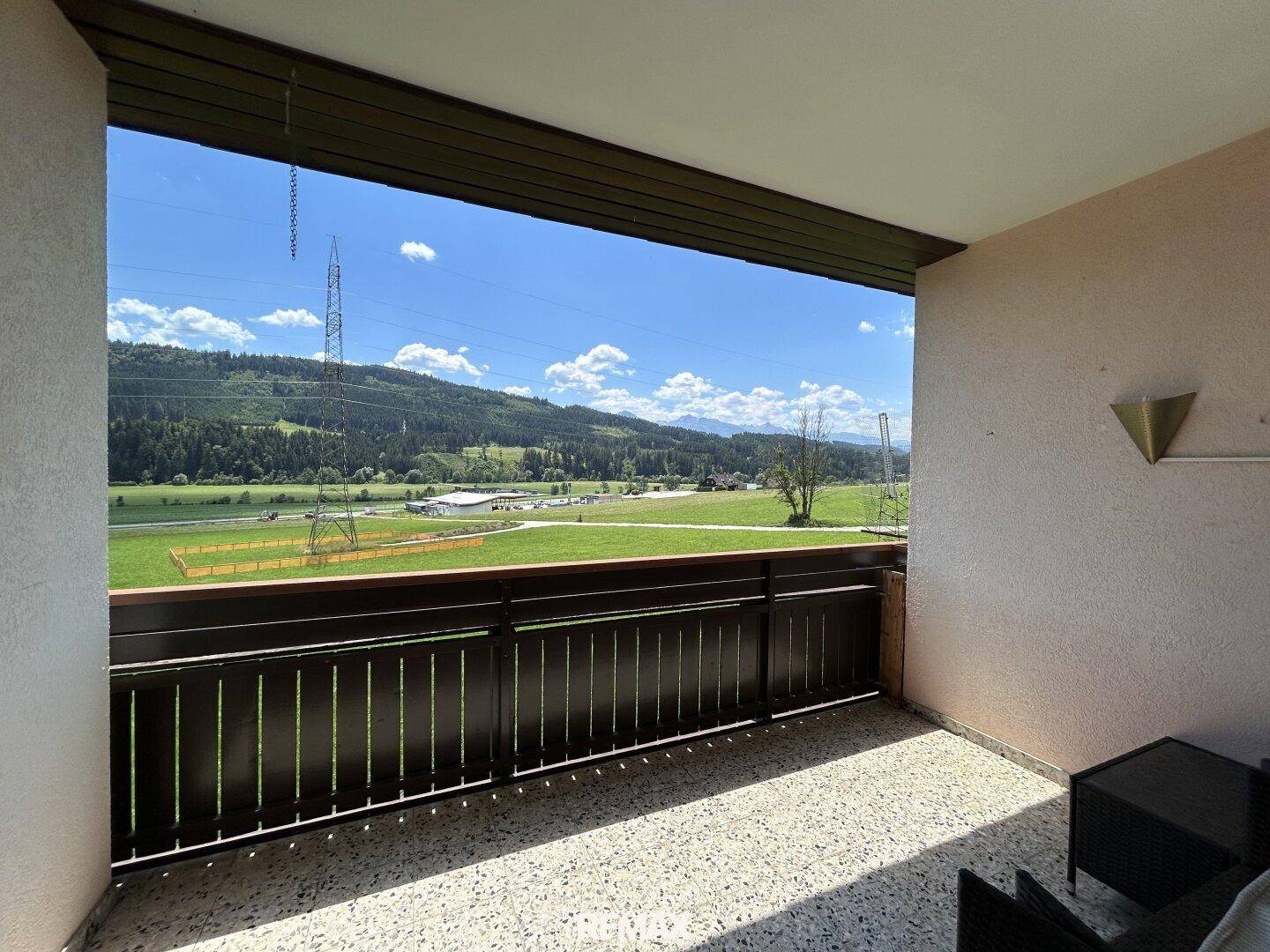Geräumiger Balkon mit weitem Blick über grüne Felder und Berge.