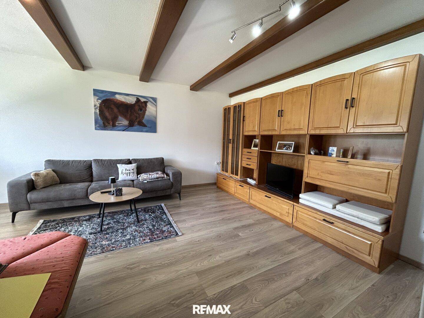 Gemütliches Wohnzimmer mit Holzbalken, Laminatboden und traditionellen Holzmöbeln.