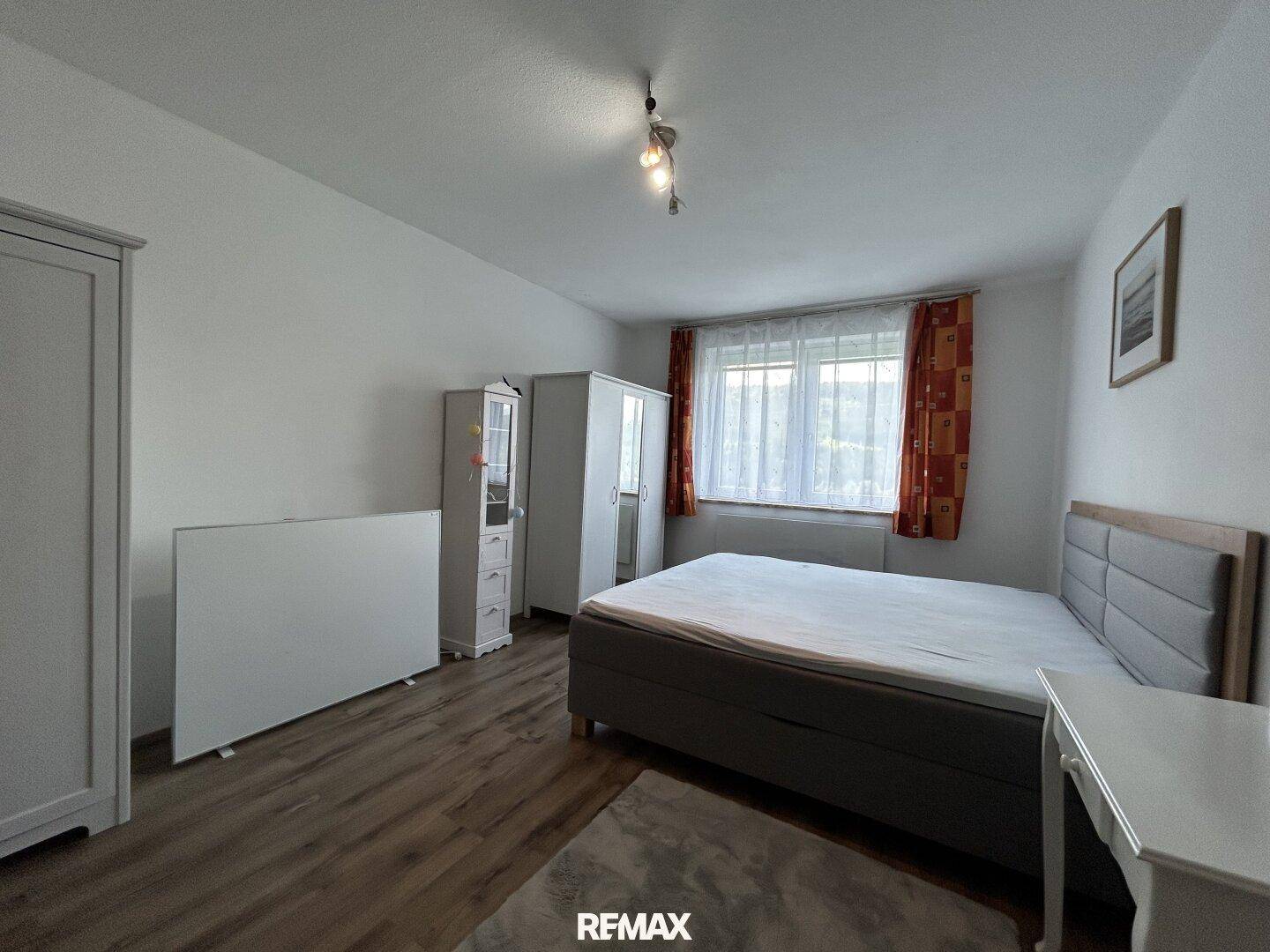 Schlafzimmer mit Doppelbett, weißen Möbeln und Fenster mit Ausblick.