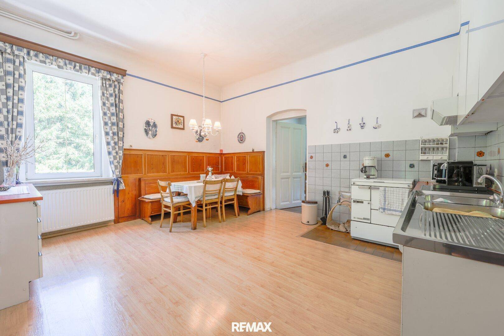 Geräumige Wohnküche mit Holzboden, Essbereich und traditionellen Fliesen an der Wand.