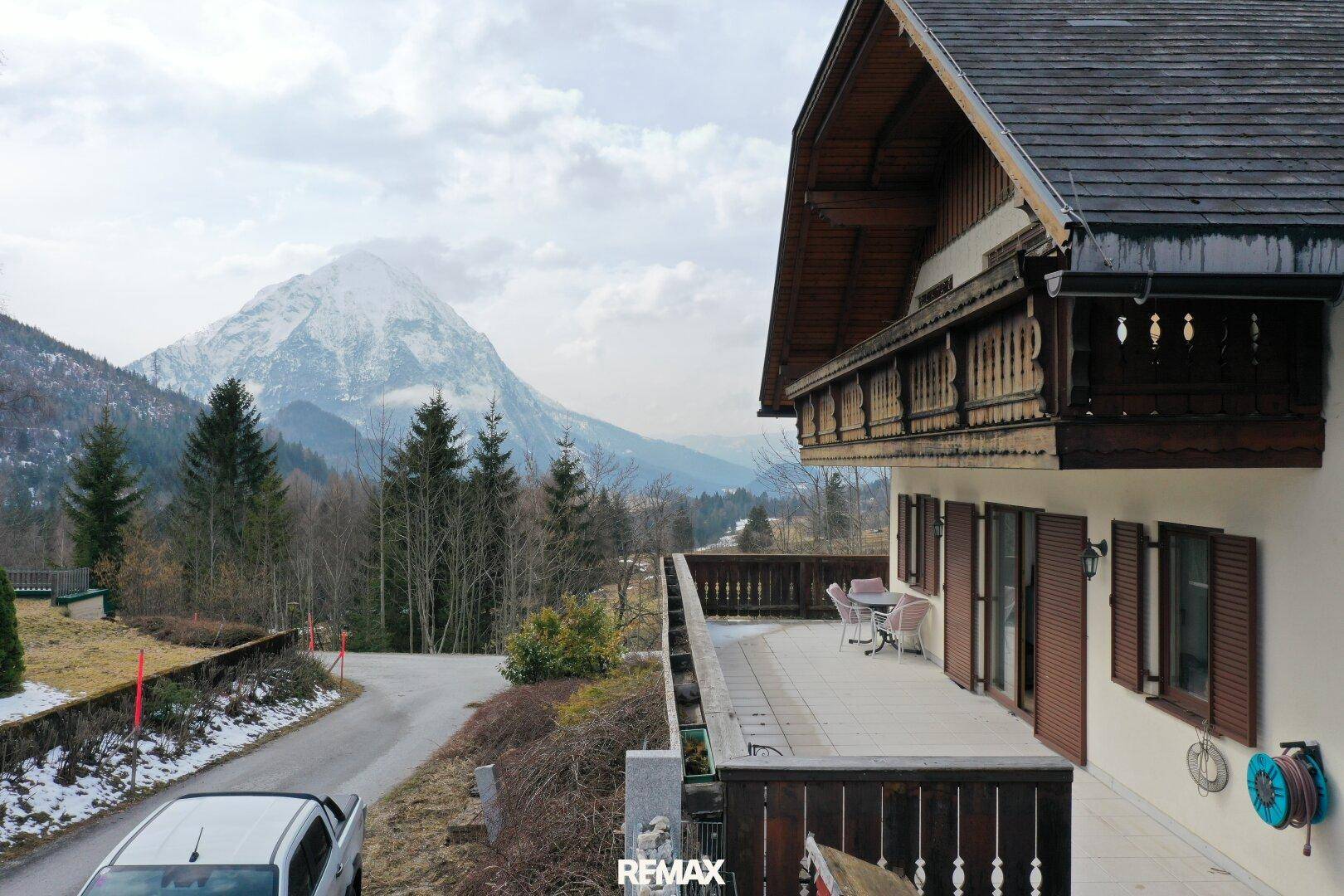 Winterliche Terrasse mit Gartenmöbeln und einem beeindruckenden Blick auf die verschneiten Berge.