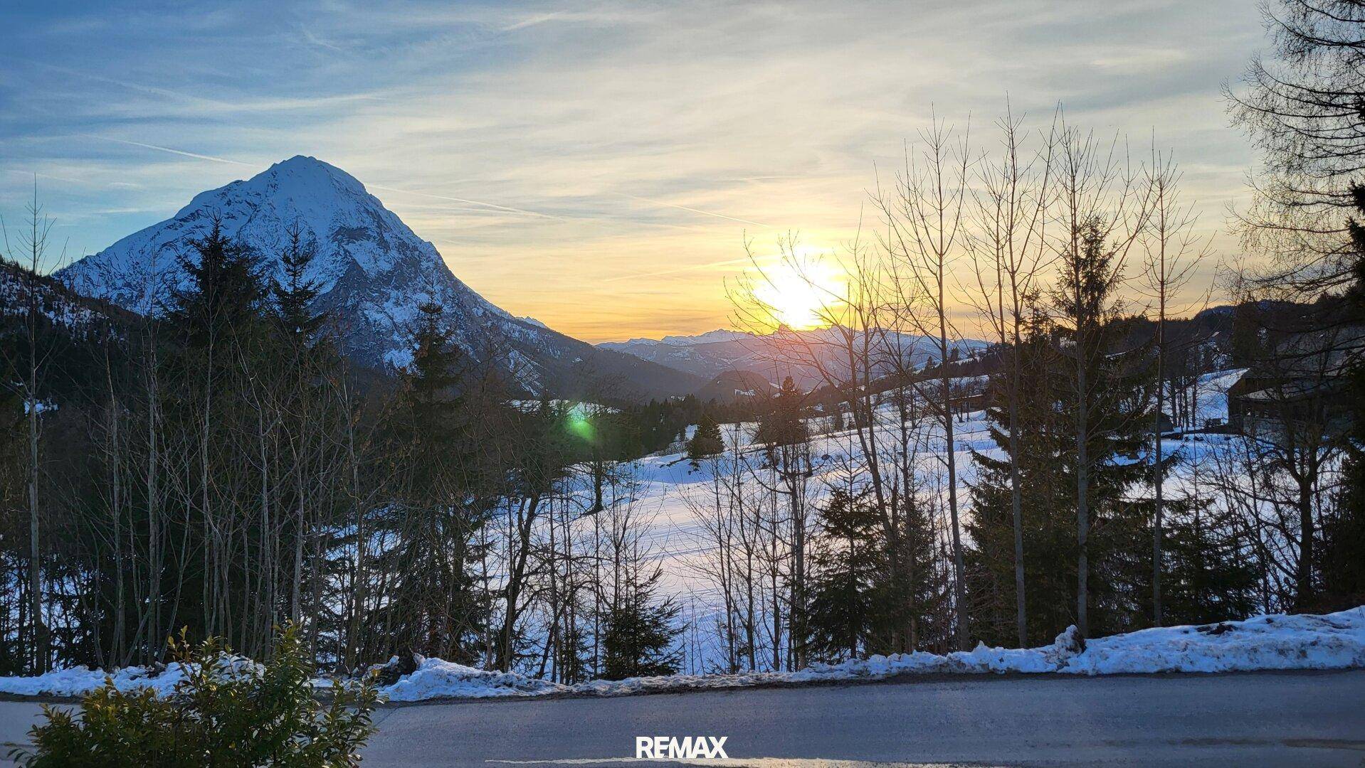 Spektakulärer Sonnenuntergang über den verschneiten Bergen und Wäldern, eine malerische Winterlandschaft.