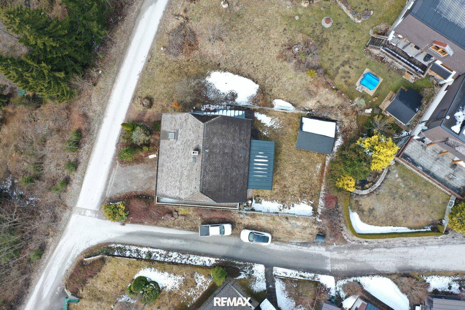 Luftaufnahme des Anwesens mit Haus, Garten und umliegender Landschaft im Winter.