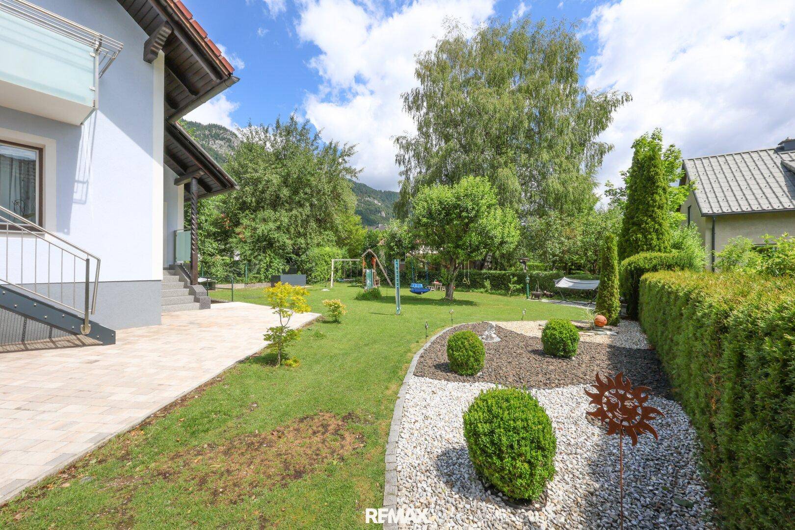 Gepflegter Gartenbereich mit Ziersträuchern, Kiesbeet und Rasenfläche neben dem Haus.