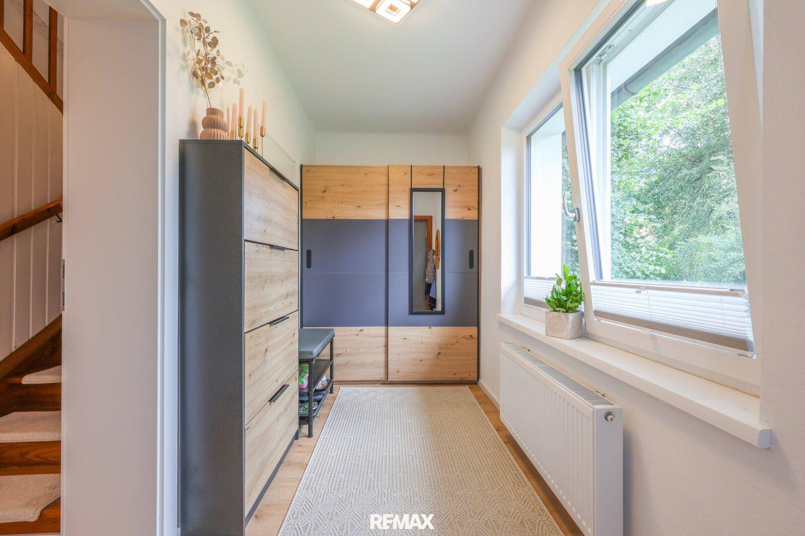Heller Eingangsbereich mit Garderobe, Schuhschrank und Fenster mit Blick ins Grüne.