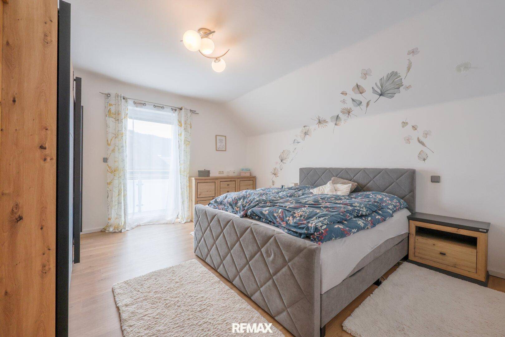 Geräumiges Schlafzimmer mit Doppelbett, Holzboden und Fenster mit Blick ins Grüne.