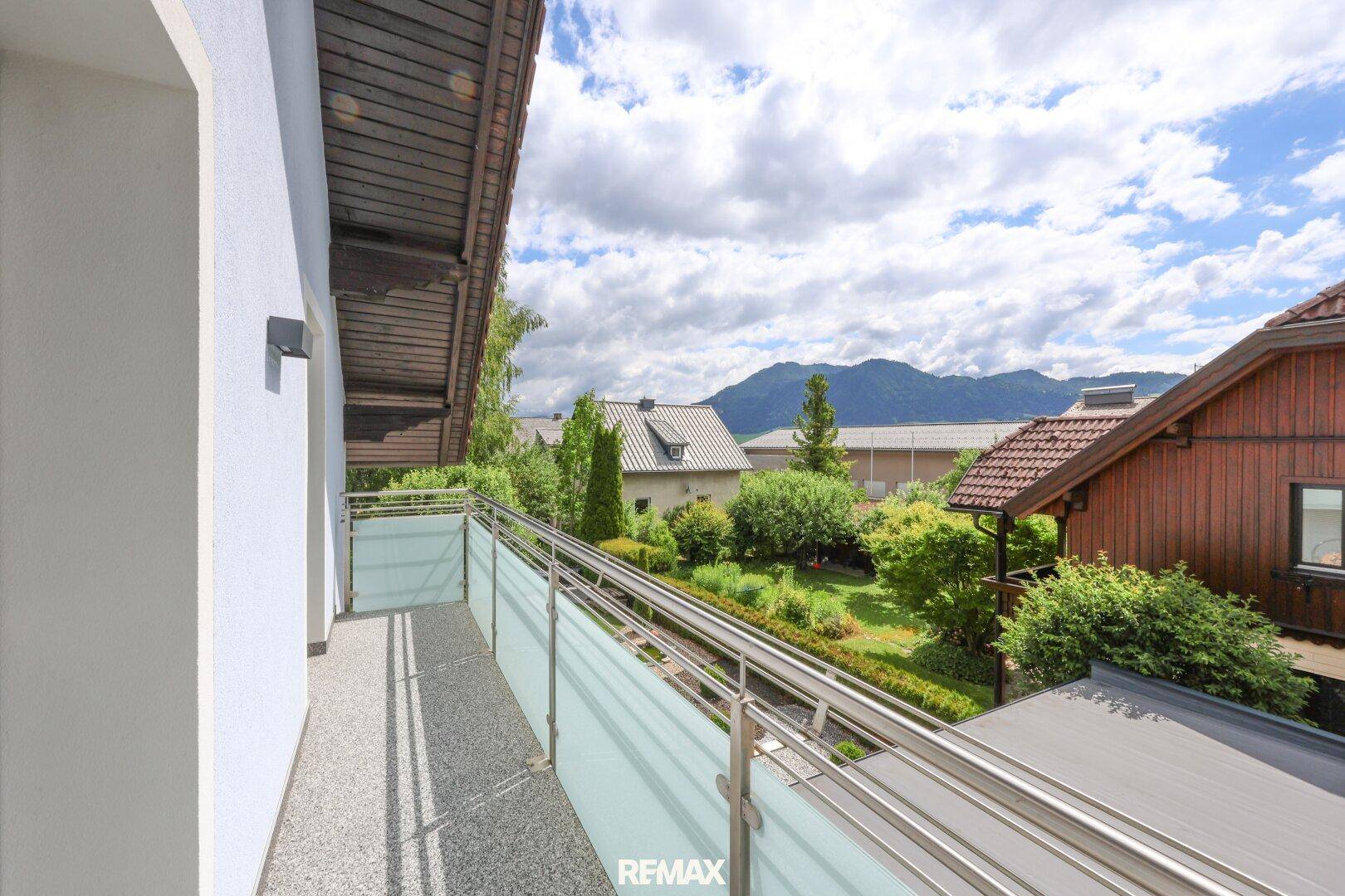 Langer Balkon mit Glasgeländer und weitem Blick auf die umliegende Berglandschaft.