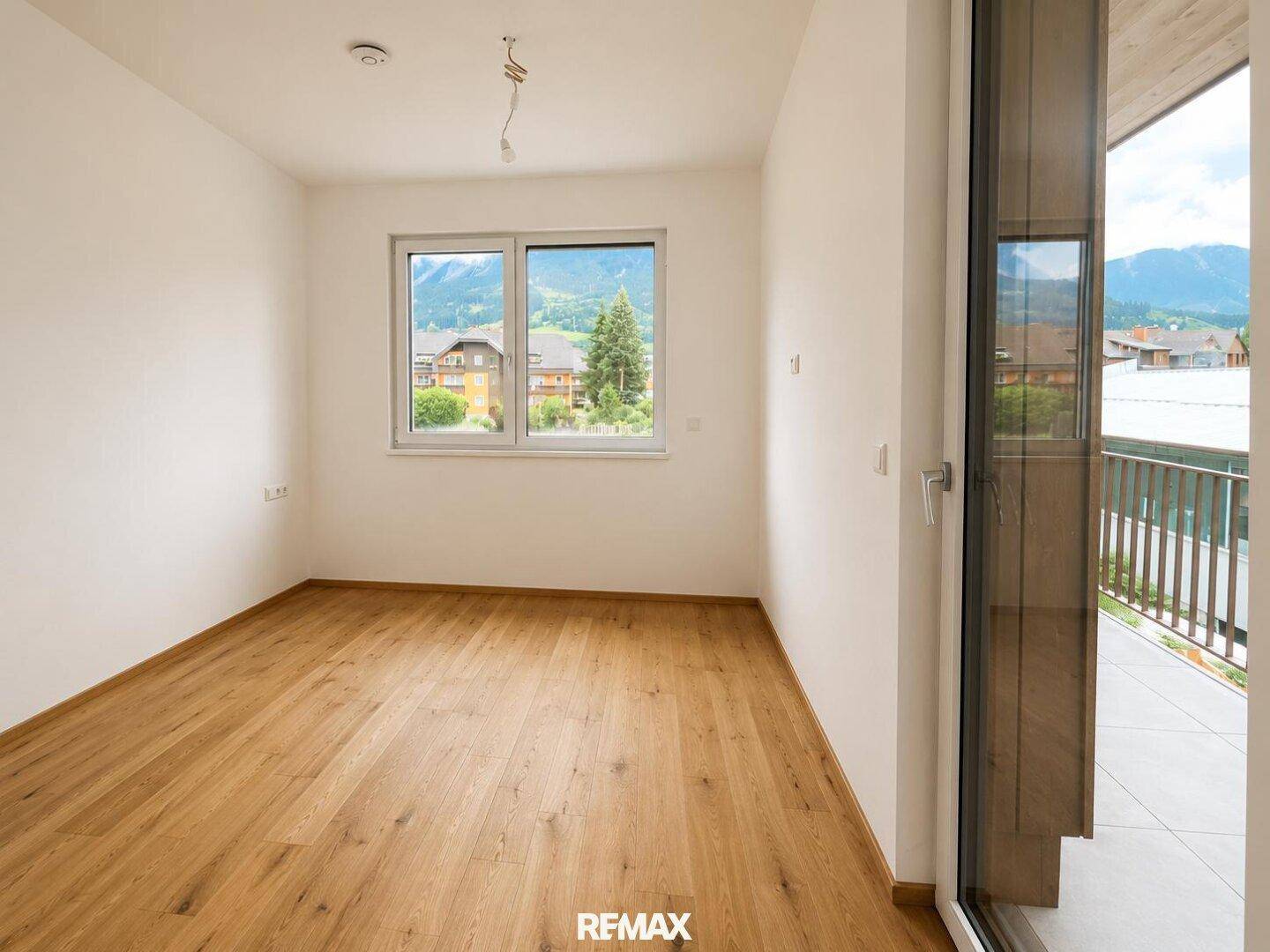 Leeres Schlafzimmer mit Holzboden und Balkonzugang, bietet viel Gestaltungspotenzial.
