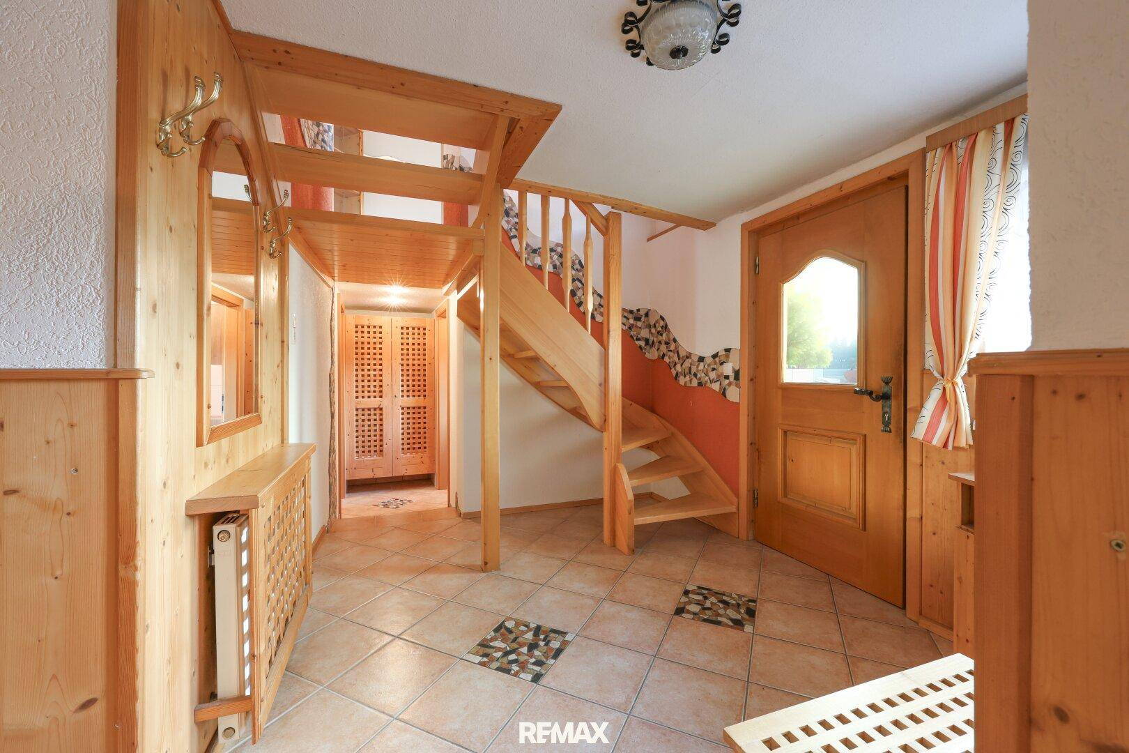 Gemütlicher Eingangsbereich mit rustikalen Holzvertäfelungen, gefliestem Boden und Holztreppe.