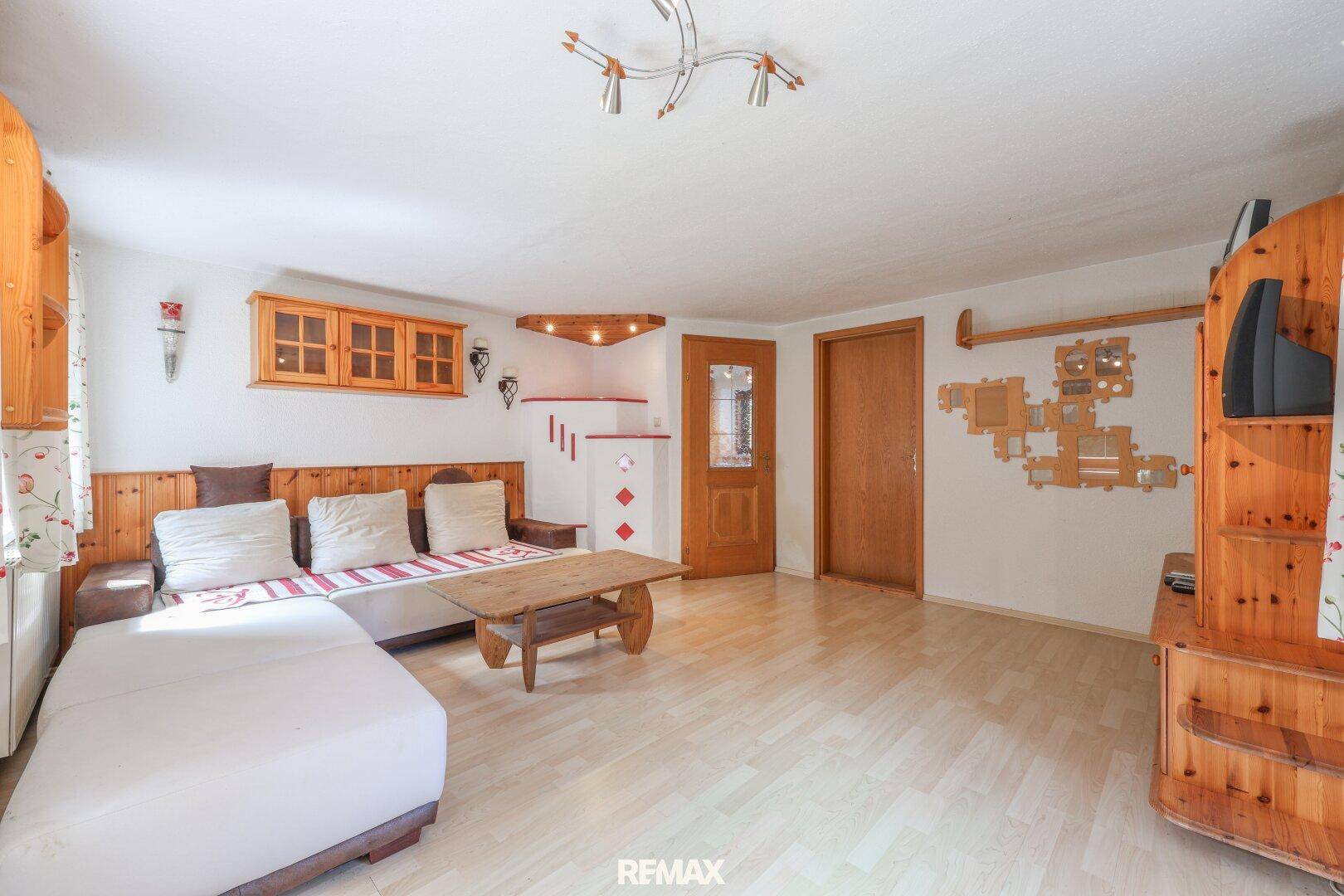 Helles Wohnzimmer mit Holzmöbeln, bequemer Couch und hellem Laminatboden.