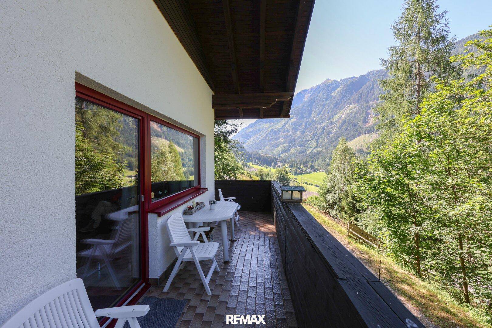 Gemütlicher Balkon mit Sitzgelegenheiten und weitem Panoramablick auf die umliegenden grünen Täler.