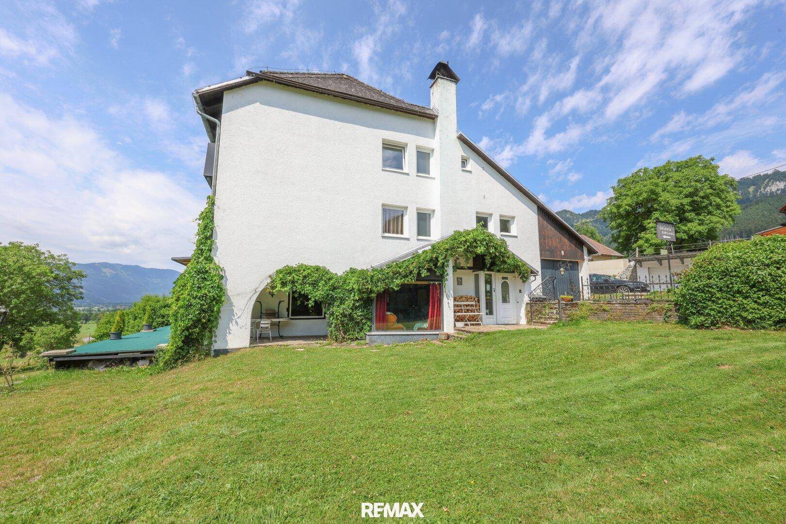 Seitenansicht des Hauses mit begrüntem Eingangsbereich und weitem Blick über die Landschaft.