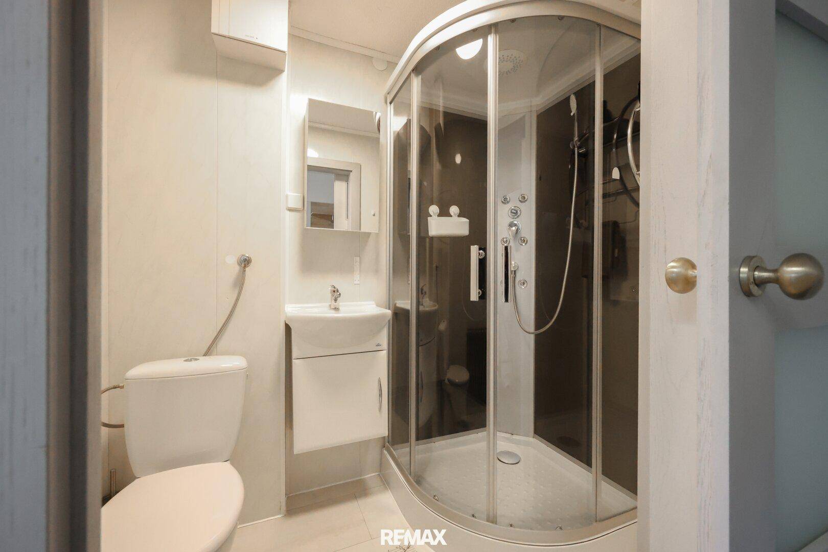 Kleines Badezimmer mit Duschkabine, WC und Waschbecken, funktional und hell gestaltet.