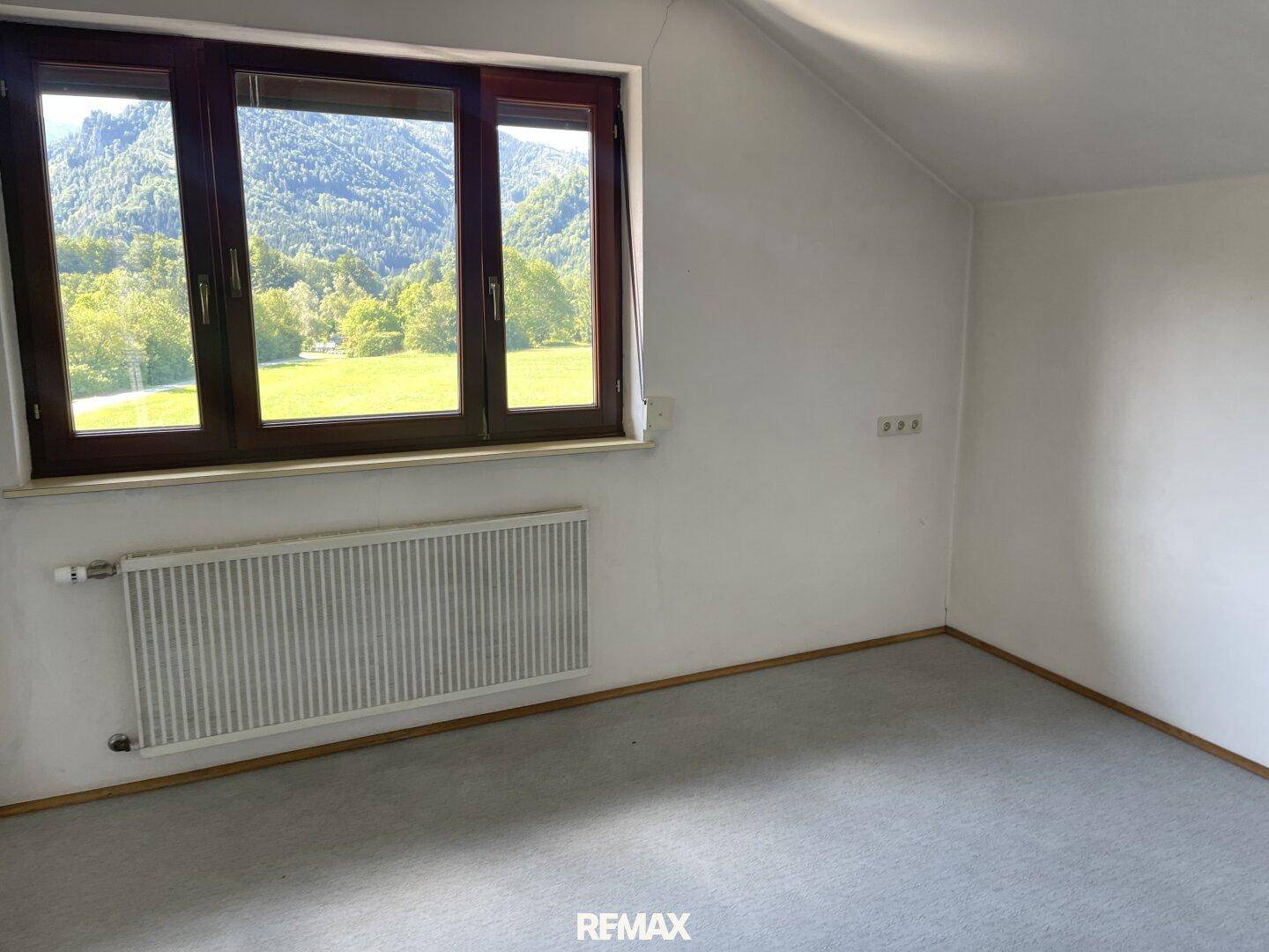Helles Zimmer mit Teppichboden, Dachschräge und weitem Bergblick.