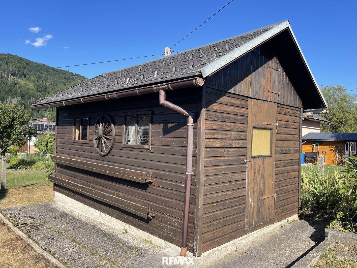 Rustikaler Holzschuppen im Garten mit traditionellen Dekorationselementen.