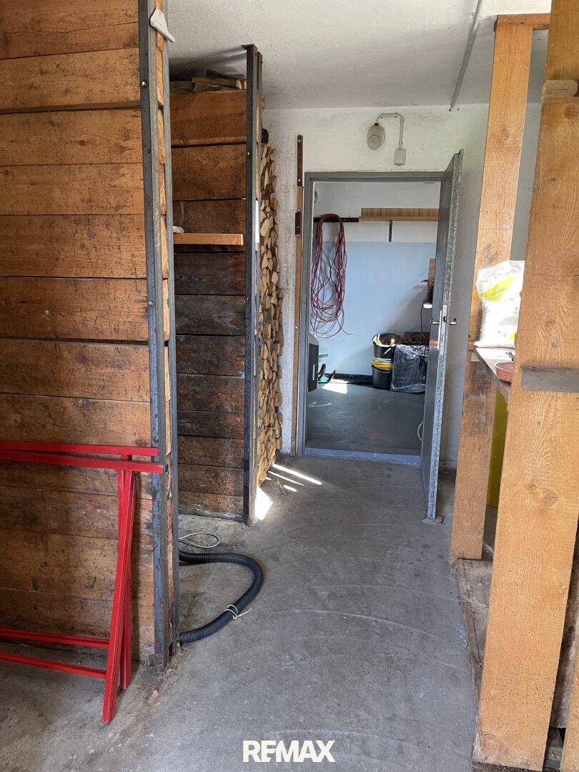 Lagerraum im Keller mit Holzstapeln und Regalen für diverse Gegenstände.