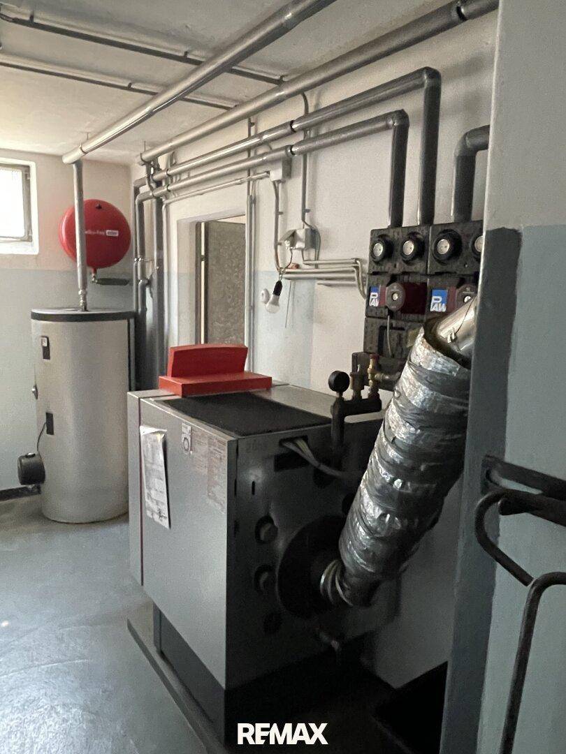 Heizungsraum im Keller mit Kessel, Warmwasserspeicher und Rohrleitungen.