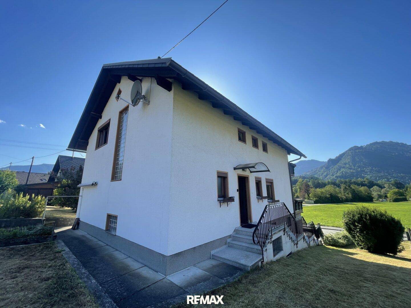 Seitenansicht des Hauses mit Eingangsbereich und Treppe, umgeben von Natur.