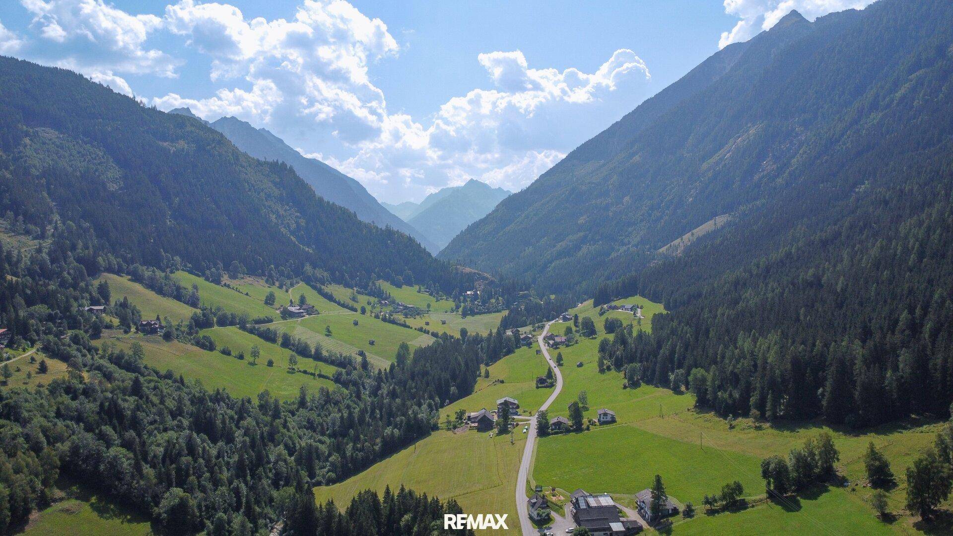 Eine malerische Talansicht mit grünen Wäldern, Wiesen und einer Straße, die sich durch die Landschaft schlängelt.