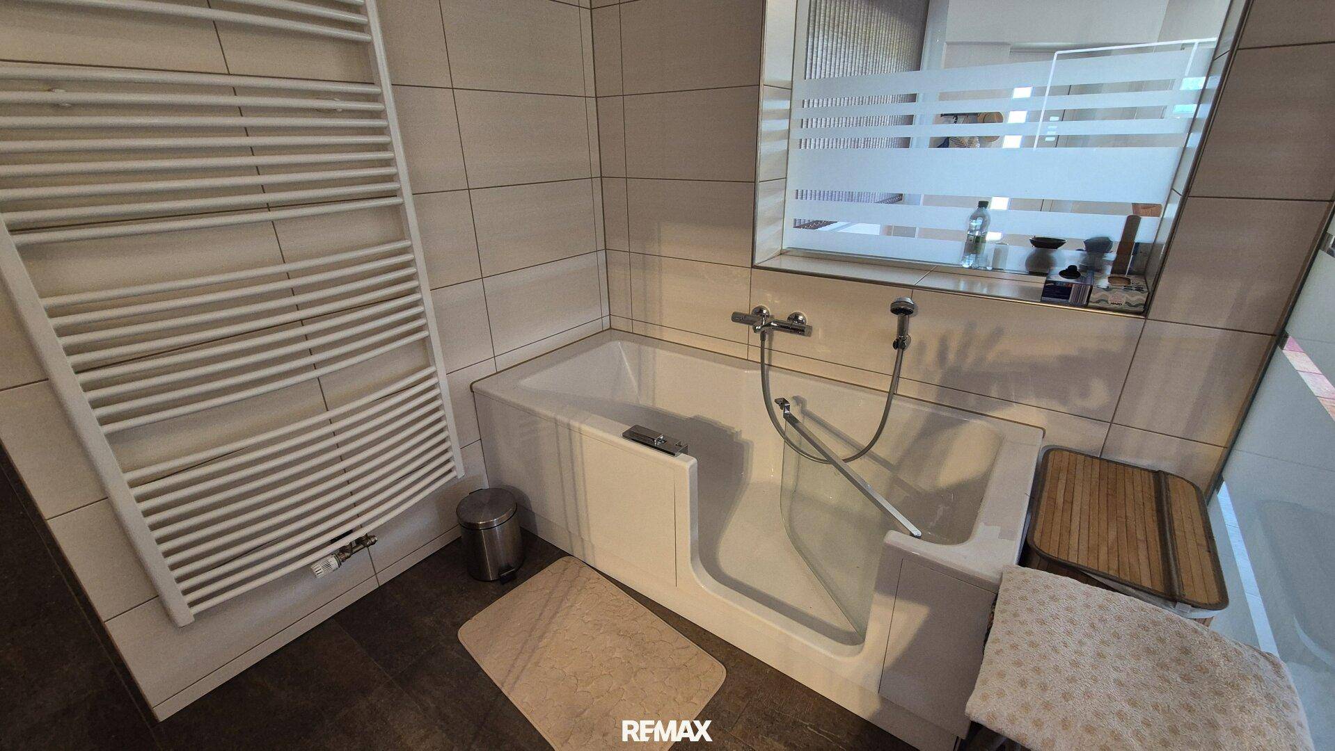 Modernes Badezimmer mit barrierefreier Badewanne und beheiztem Handtuchhalter.