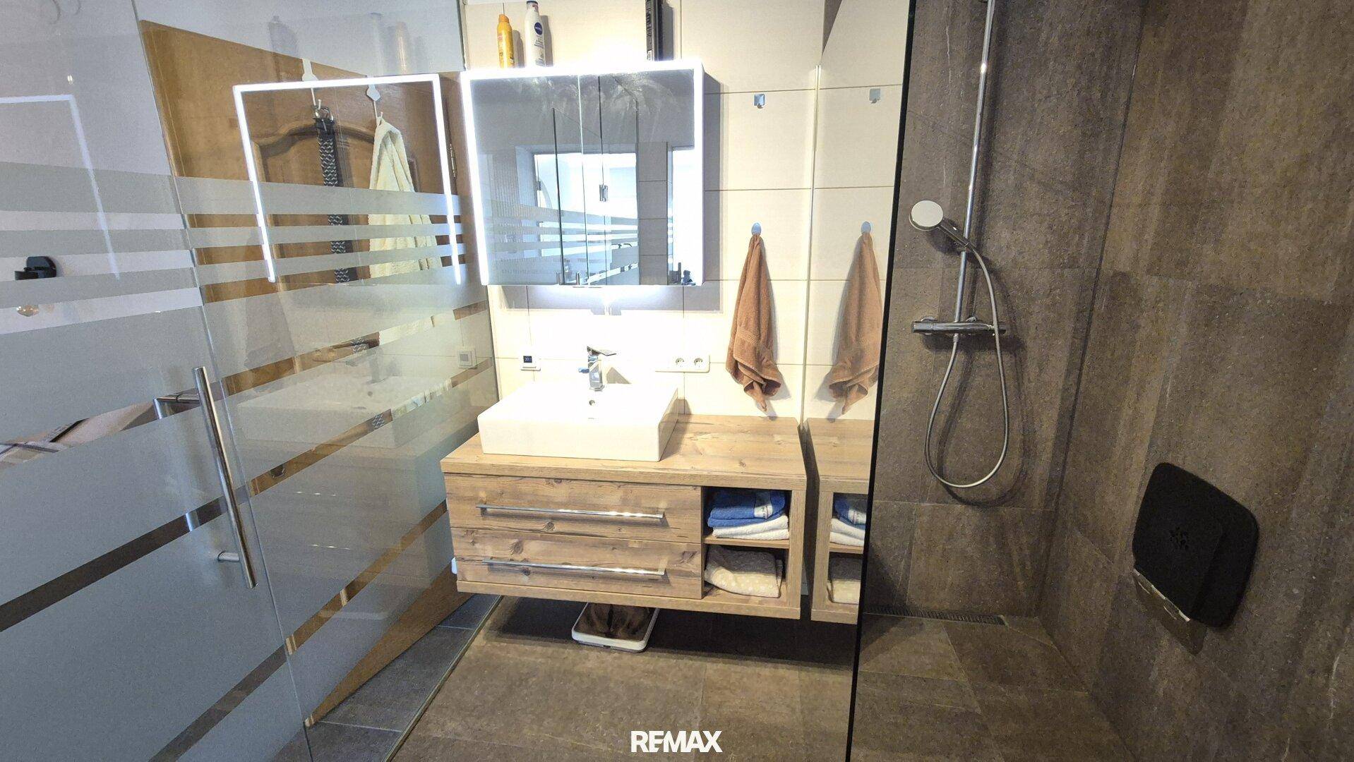 Elegantes Badezimmer mit begehbarer Dusche, modernem Waschtisch und Spiegelschrank.