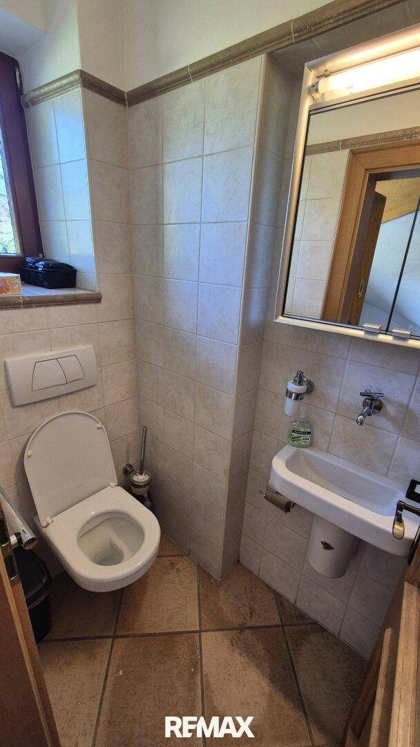 Kleines Gäste-WC mit Wand-WC, Waschbecken und Fenster für natürliche Belüftung.