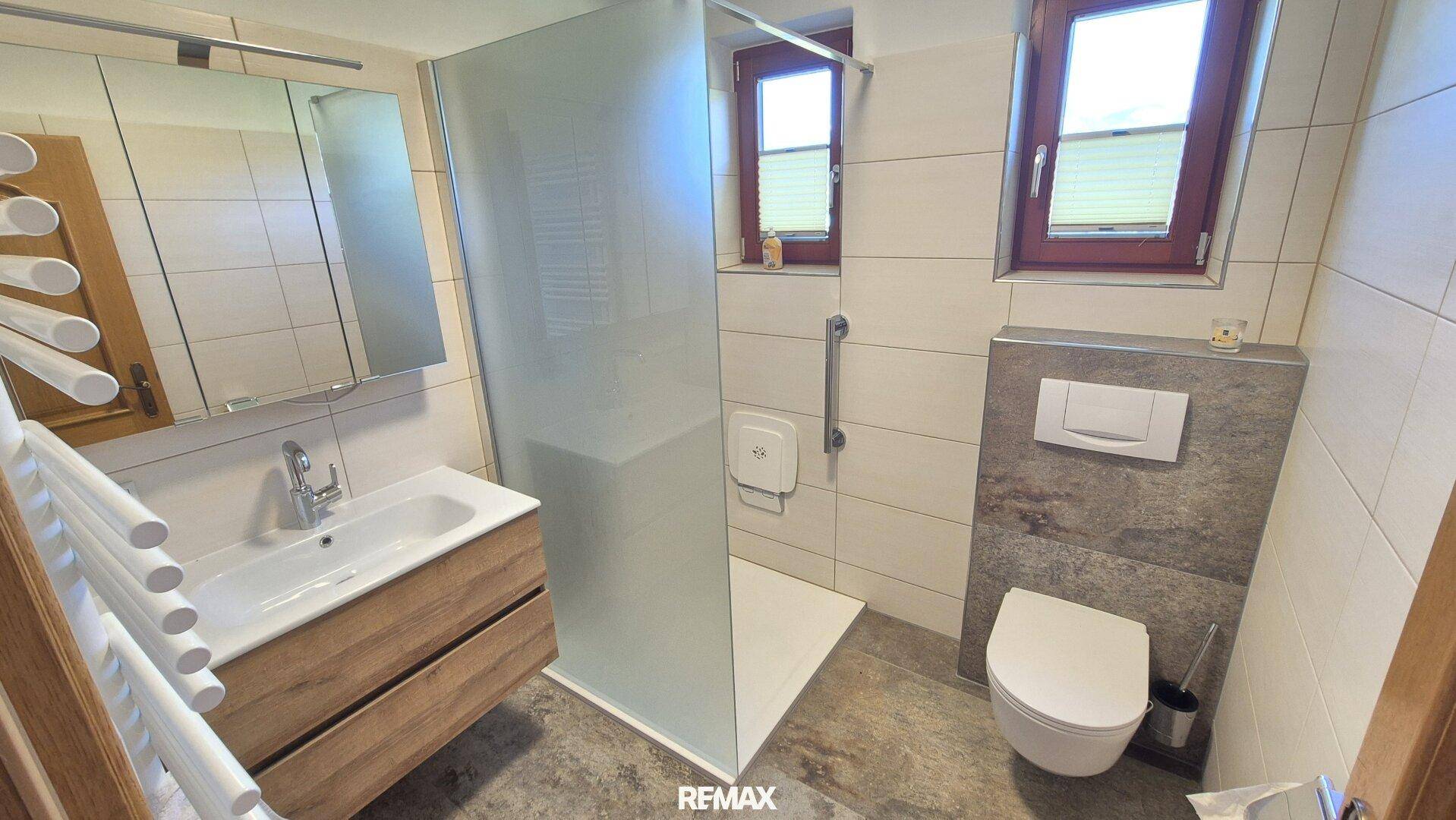 Modernes Badezimmer mit ebenerdiger Dusche, wandhängendem WC und Fenster.