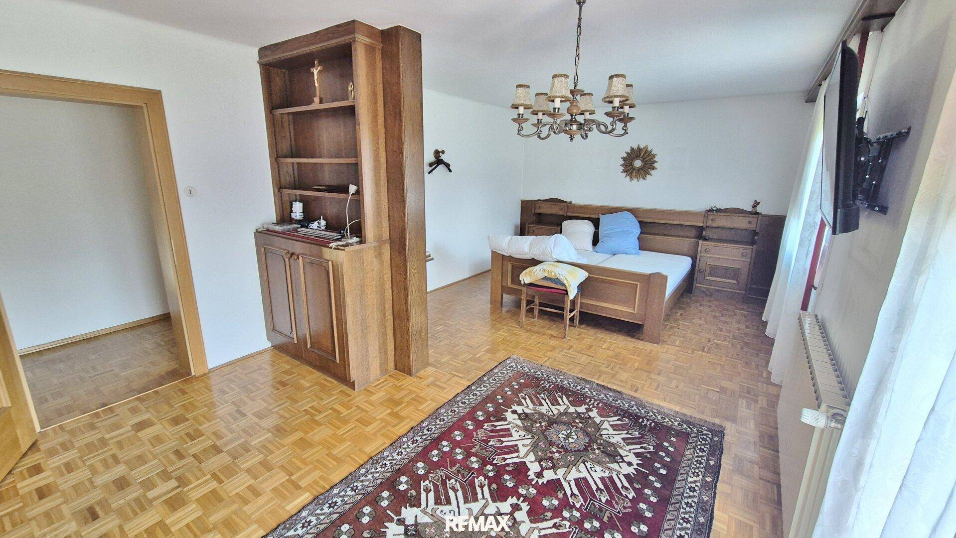 Geräumiges Schlafzimmer mit Doppelbett, Holzmöbeln und einem dekorativen Teppich.