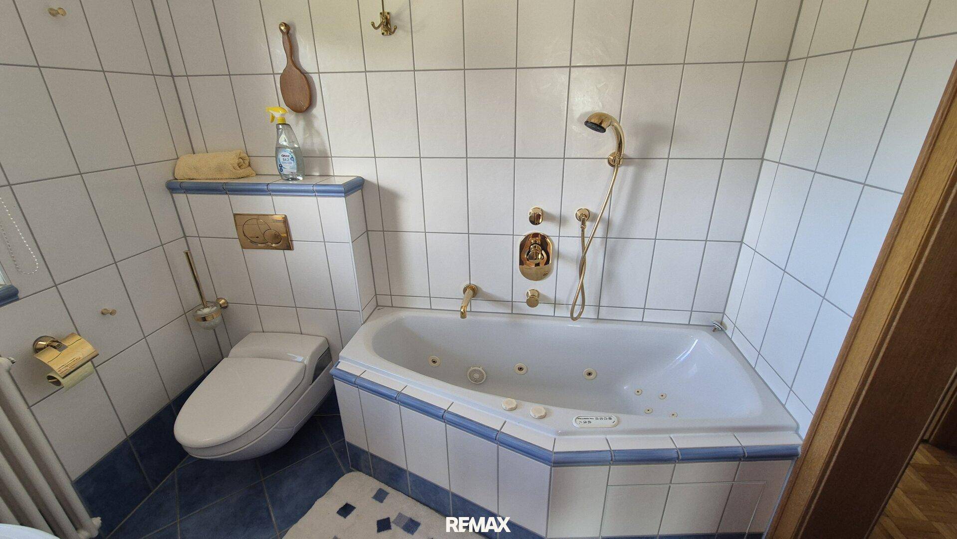 Detailansicht des Badezimmers mit Eckbadewanne und gefliestem WC-Bereich.