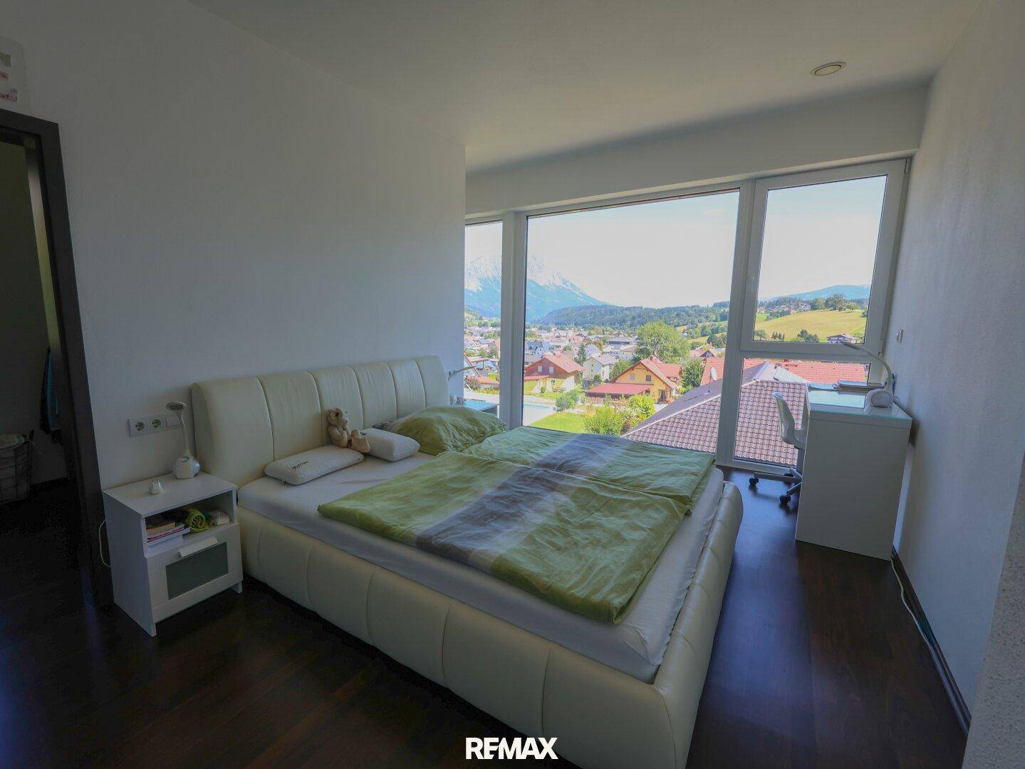 Schlafzimmer mit großen Fenstern, die einen weiten Blick auf die Umgebung bieten.