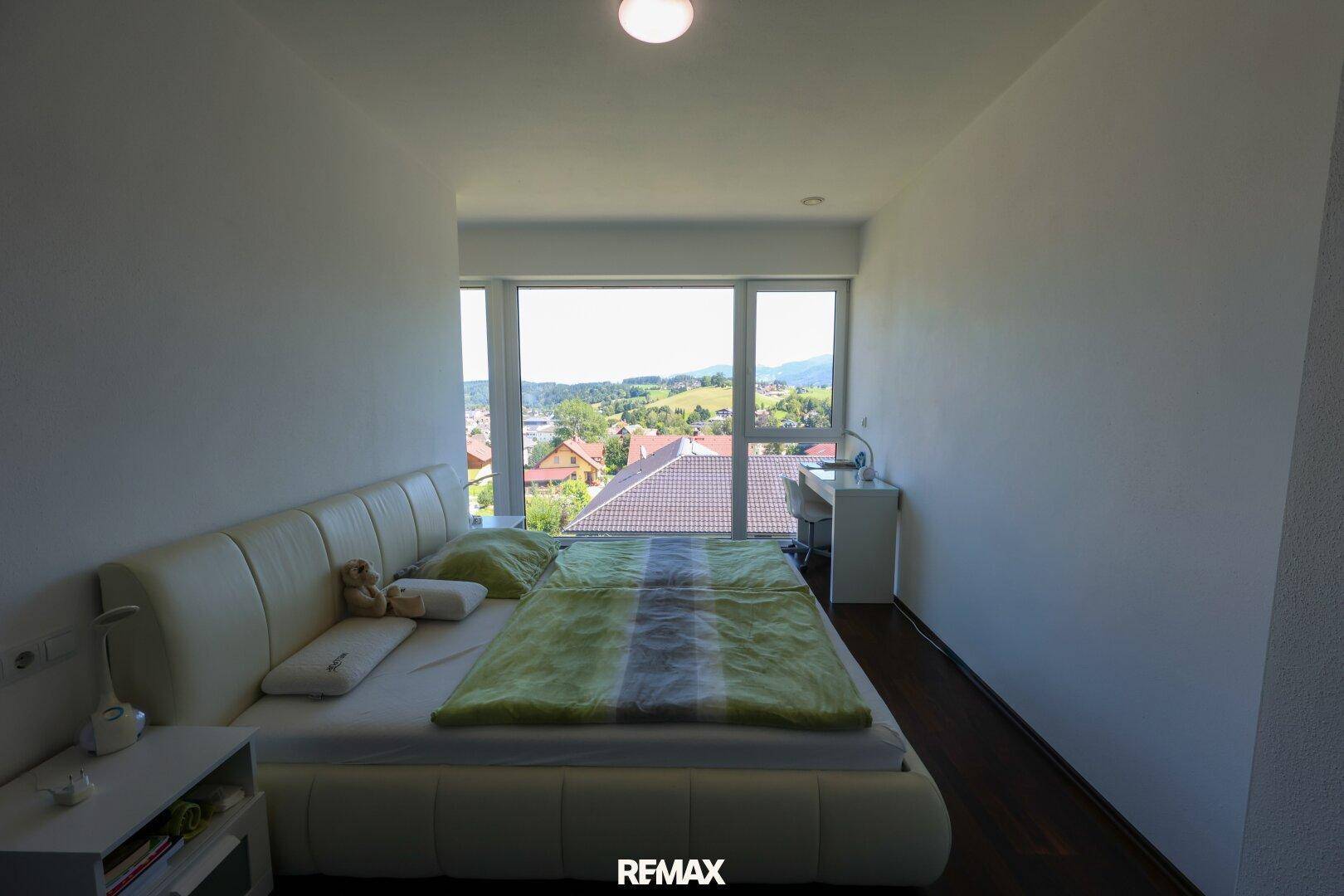 Schlafzimmer mit Panoramablick durch große Fenster auf die Landschaft.