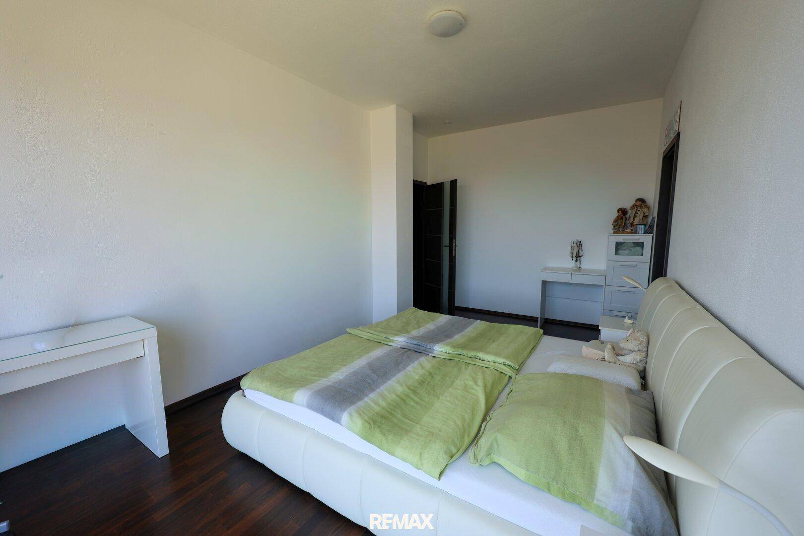 Helles Schlafzimmer mit Doppelbett, Holzboden und schlichtem Design.