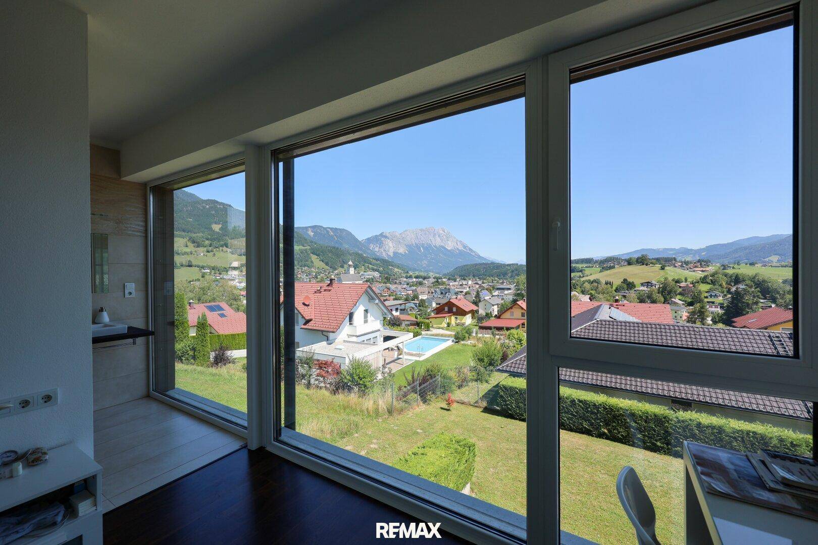 Weitläufiger Ausblick aus großen Fenstern auf die Stadt und die Berge.