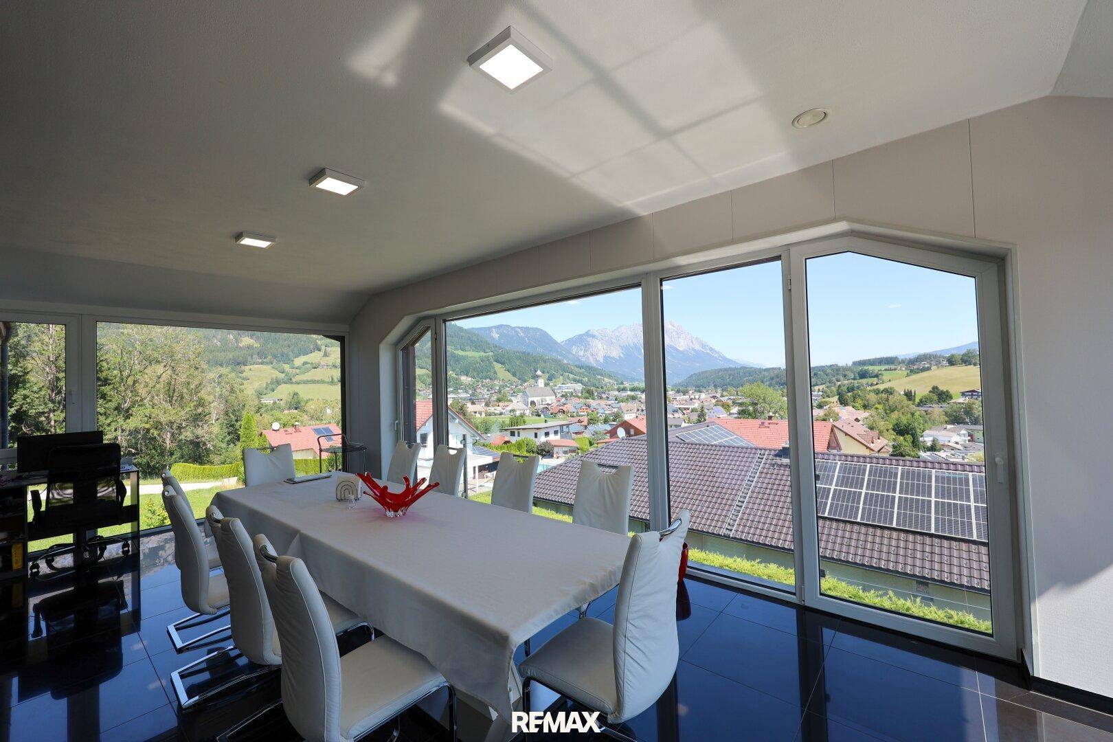 Eleganter Essbereich mit großem Tisch, weißen Stühlen und weitem Ausblick.