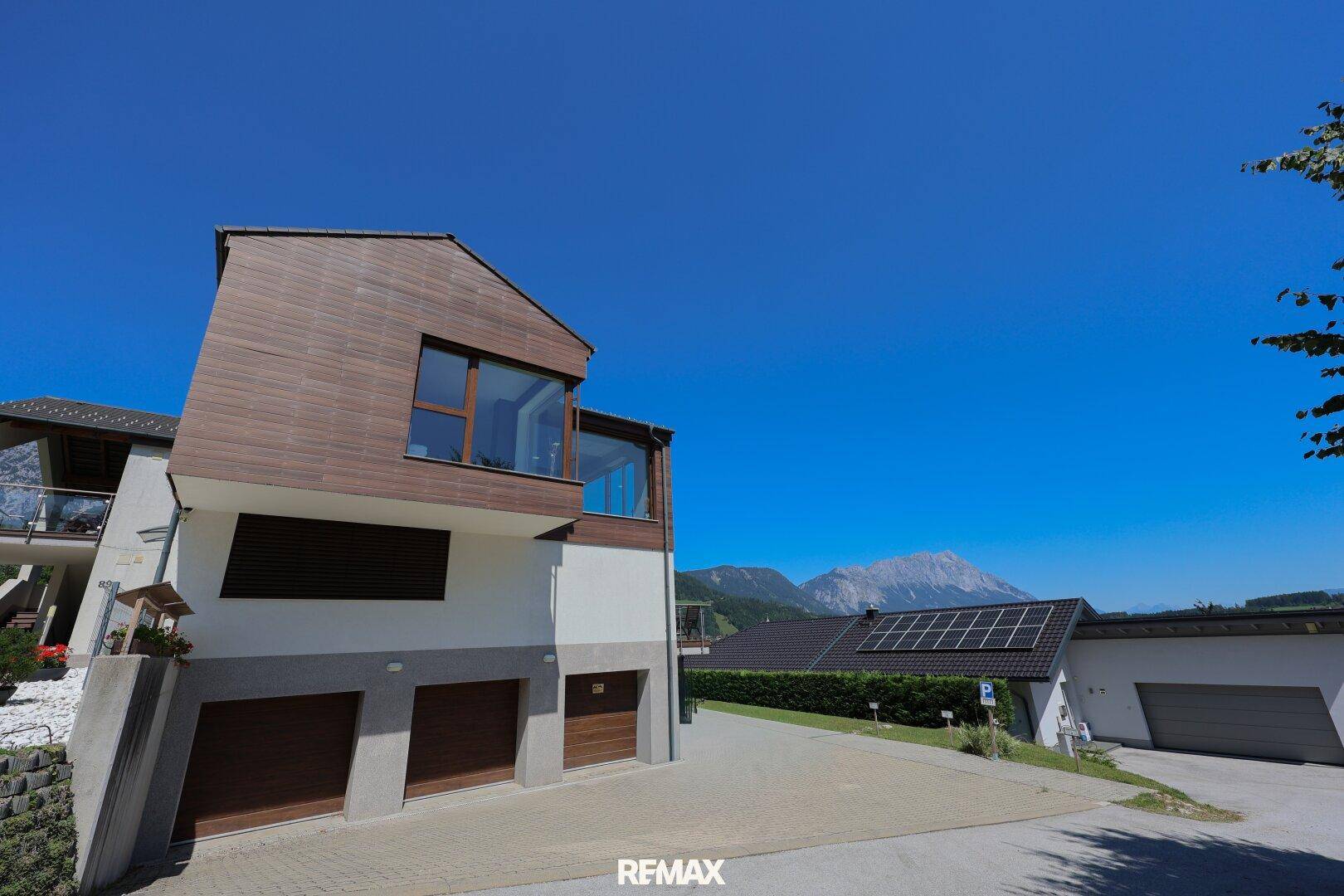 Moderne Hausfassade mit integrierten Garagen und Blick auf die Berge.